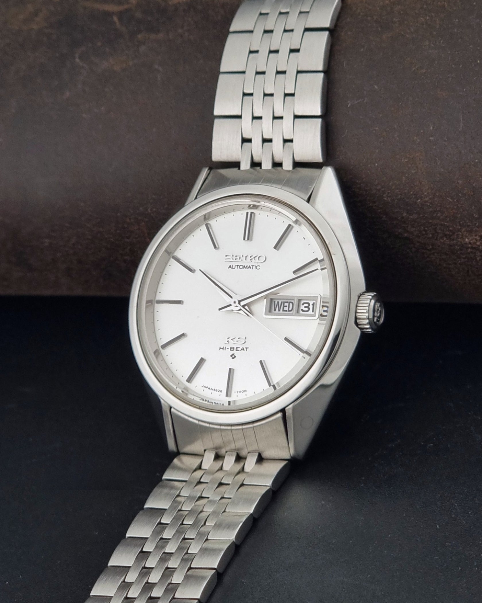 A vintage Seiko automatic watch with a silver stainless steel case and link bracelet, featuring a white dial with silver baton indices and a day-date window.