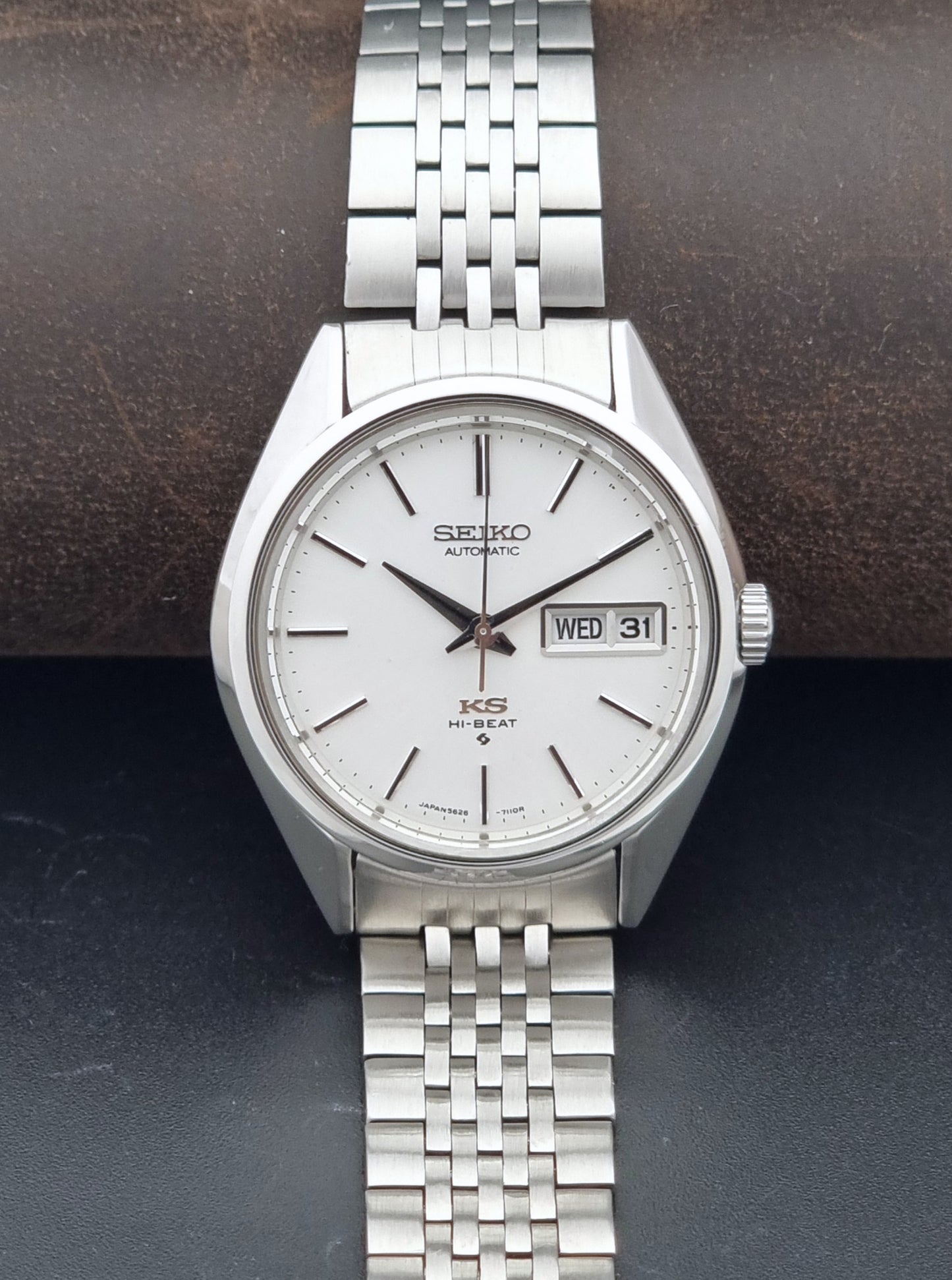 A vintage Seiko KSM Automatic watch with a silver stainless steel case and link bracelet, featuring a white dial with black hands and a day-date window.