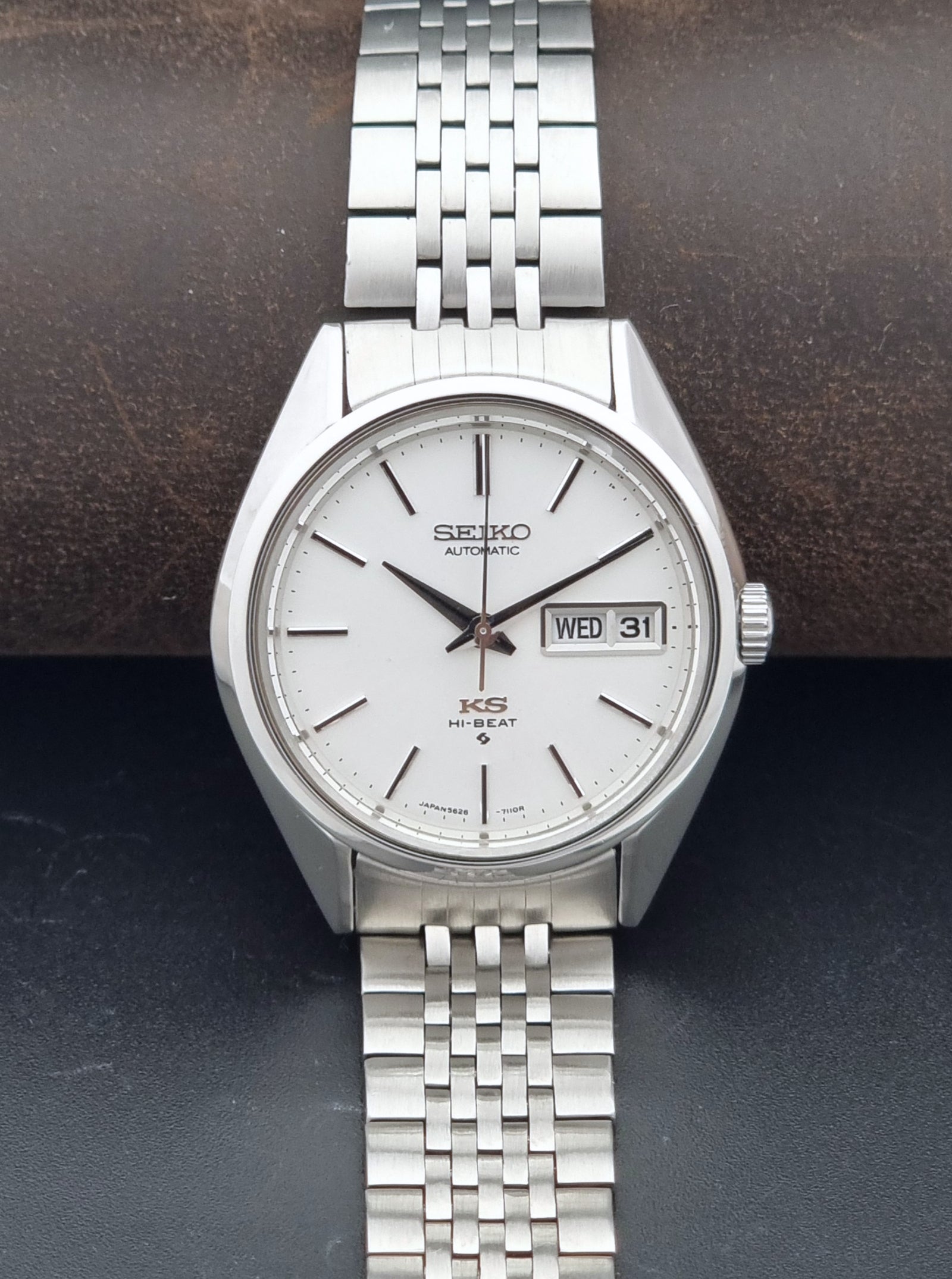 A vintage Seiko KSM Automatic watch with a silver stainless steel case and link bracelet, featuring a white dial with black hands and a day-date window.