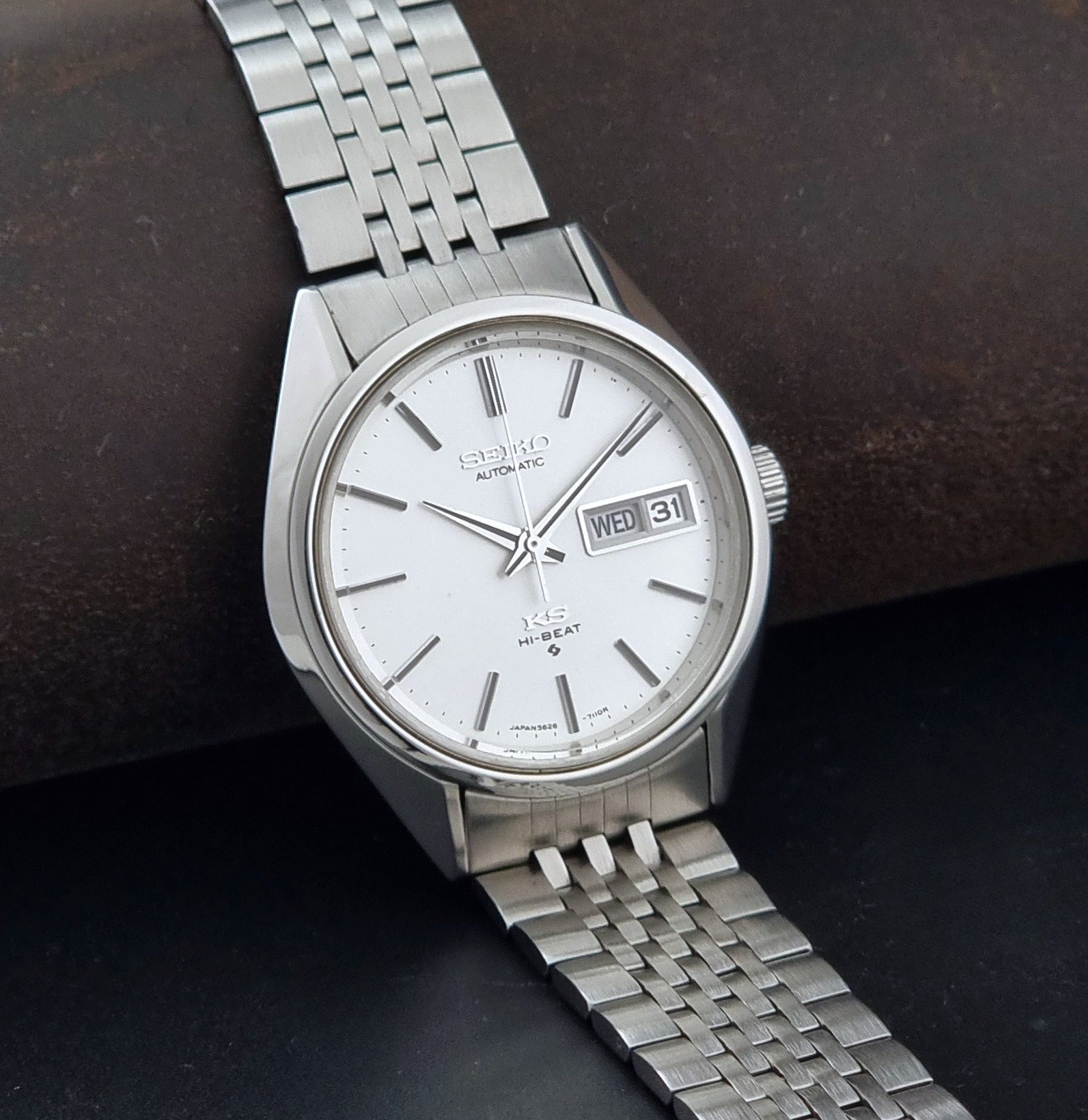 A vintage Seiko automatic watch with a silver stainless steel case and link bracelet, featuring a white dial with a day and date window.