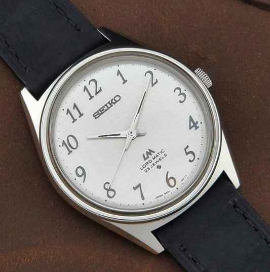 Seiko watch with black leather strap on a brown background
