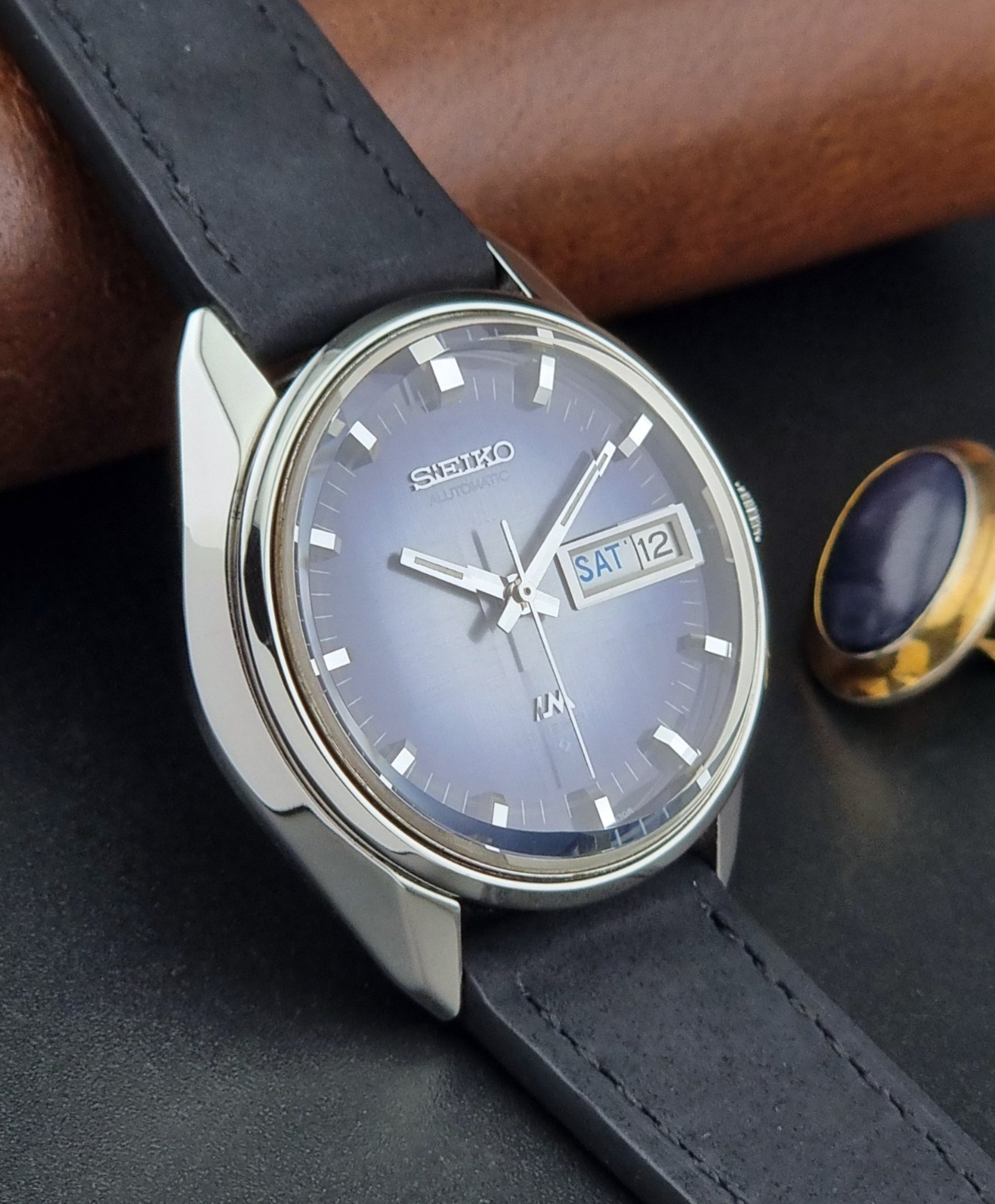 Seiko watch with black leather strap on a dark surface