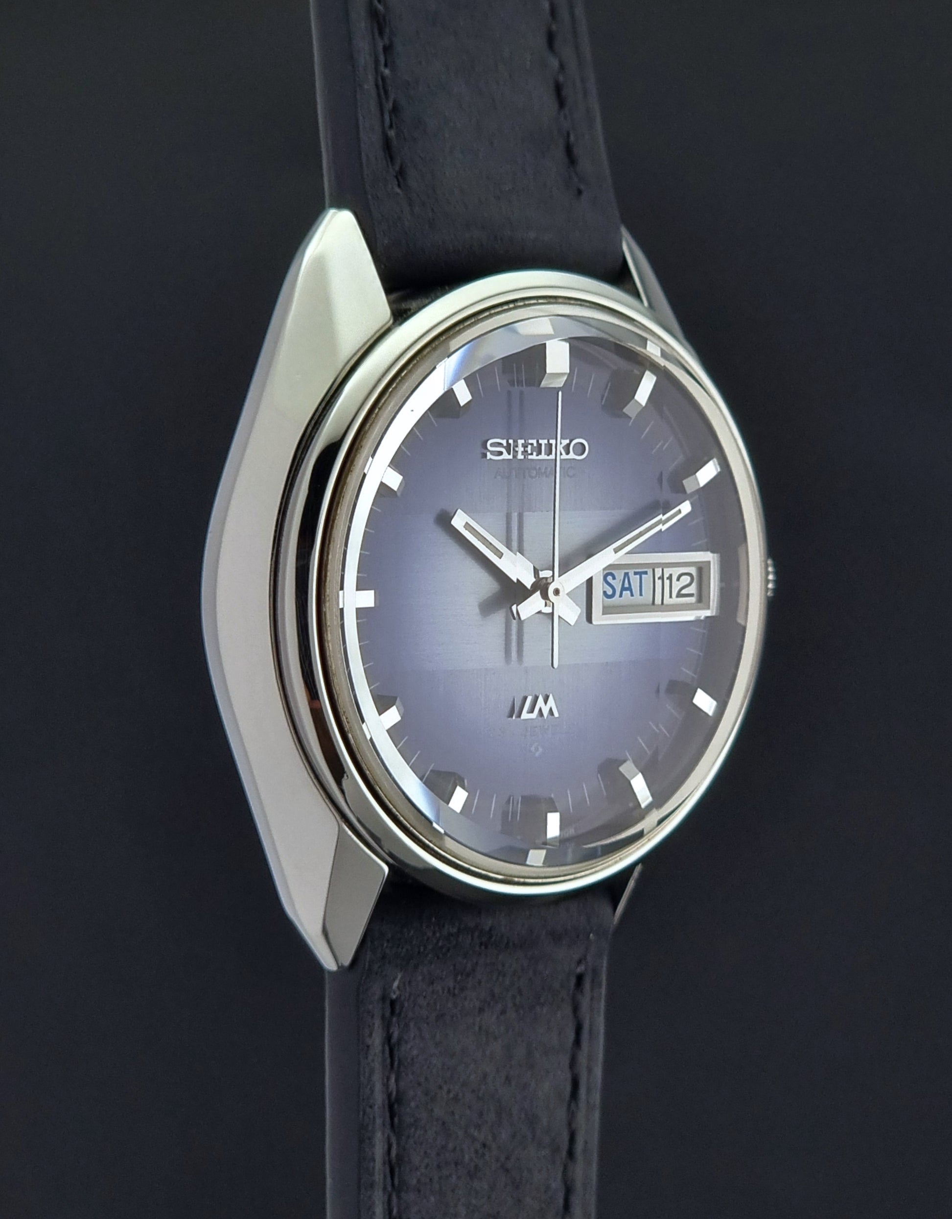 Seiko watch with black leather strap on a dark background