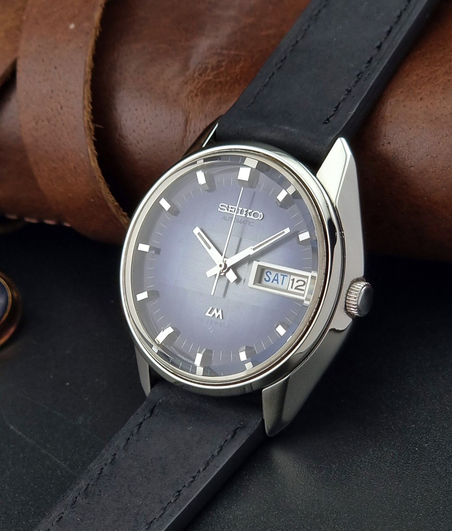 Seiko watch with black leather strap on a dark surface