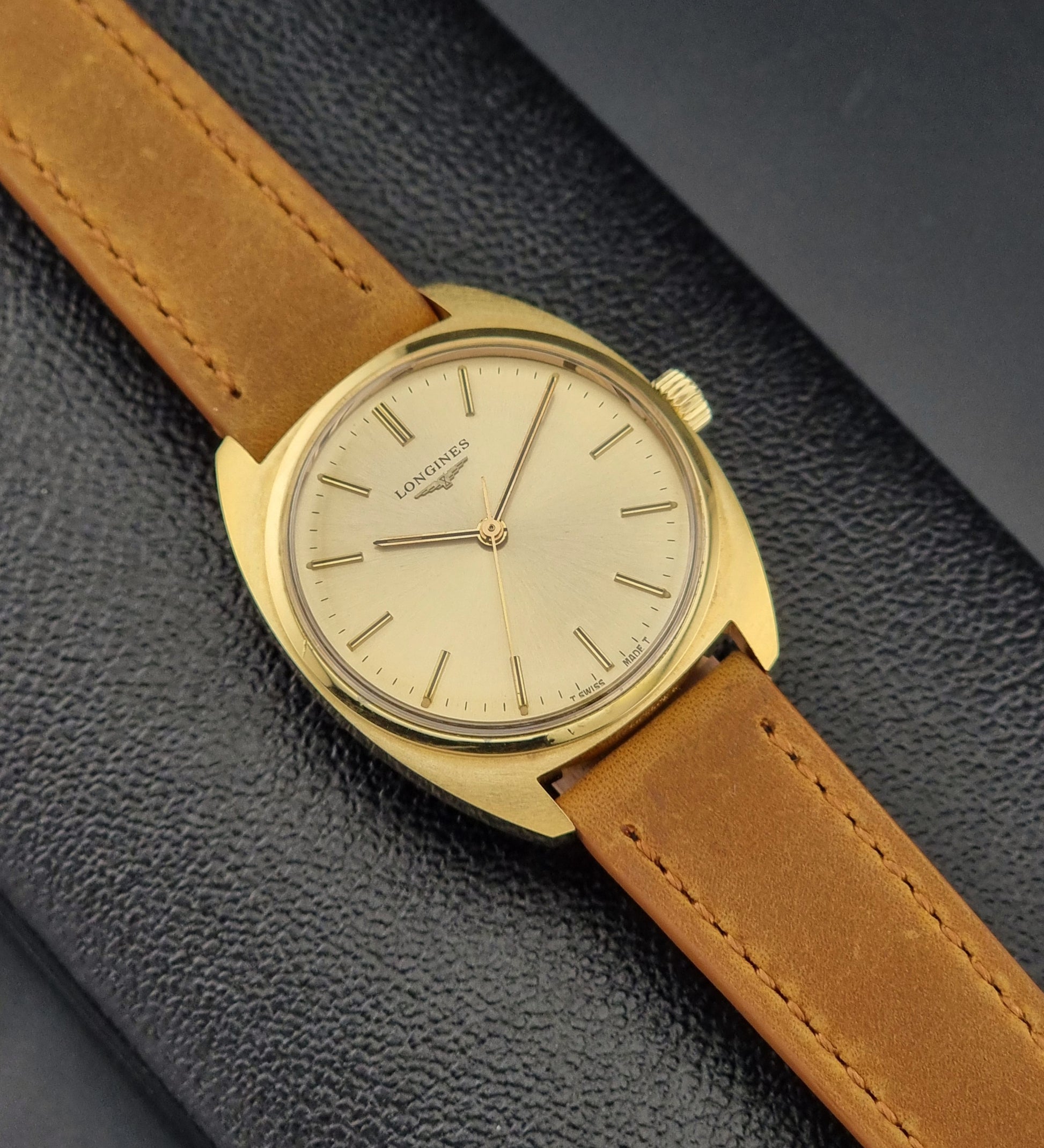 Vintage Gold Longines watch with a brown leather strap on a dark textured background