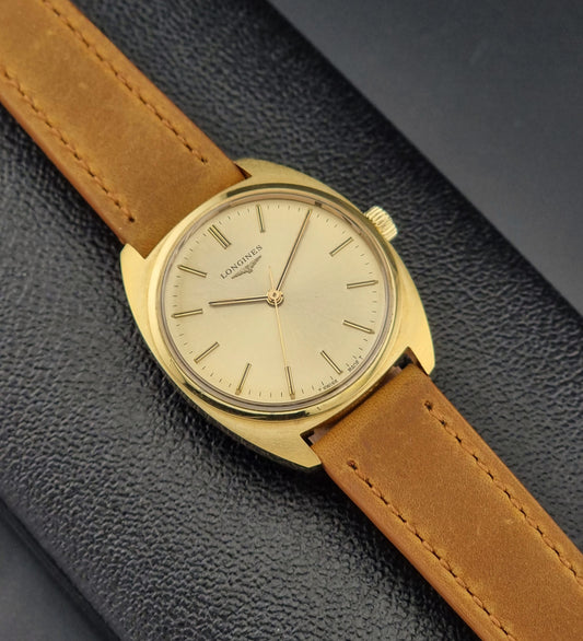 Vintage Gold Longines watch with a brown leather strap on a dark textured background