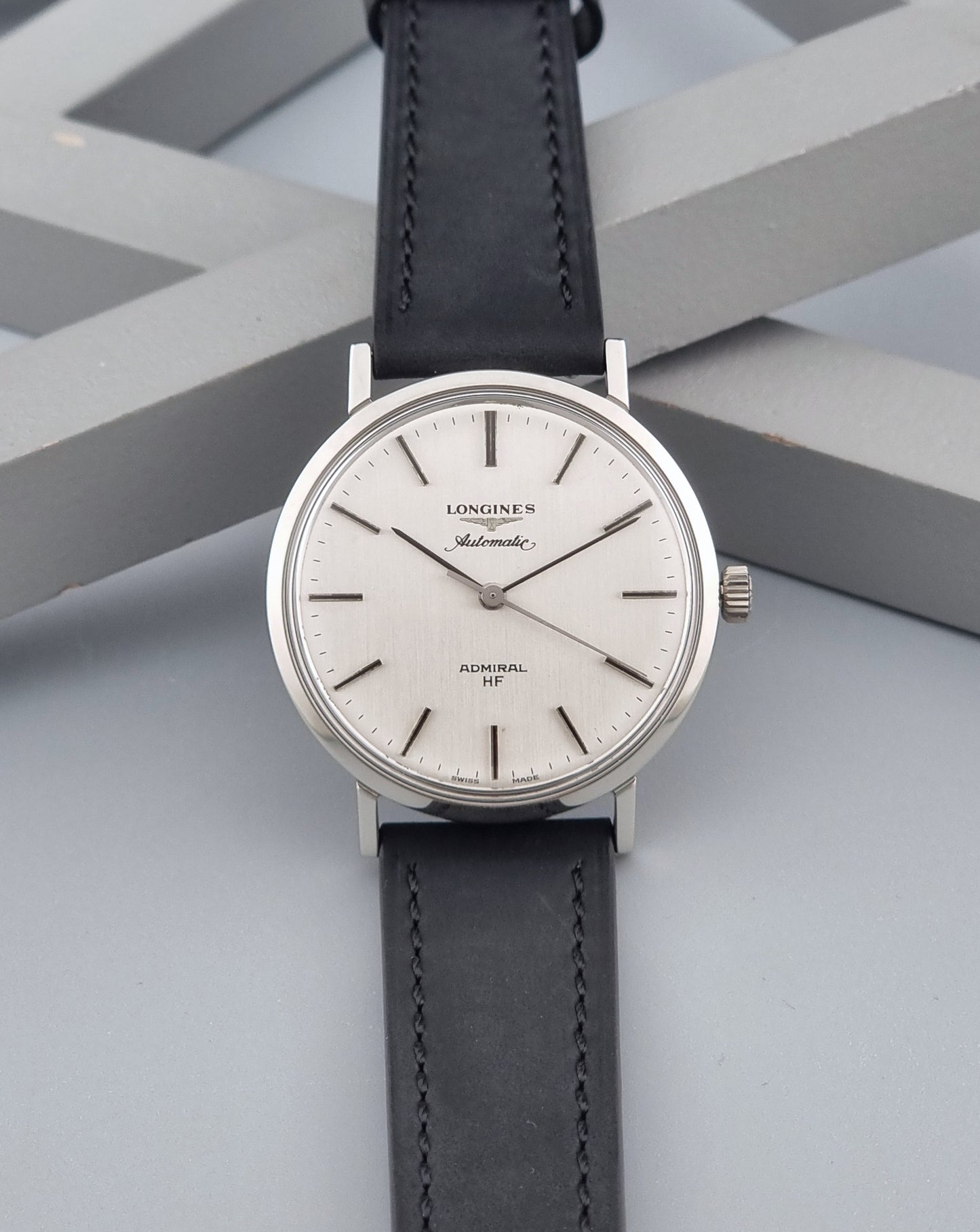 Vintage Longines Admiral Hi frequency Automatic Wristwatch 2305-1 with a black leather strap on a grey background dial view