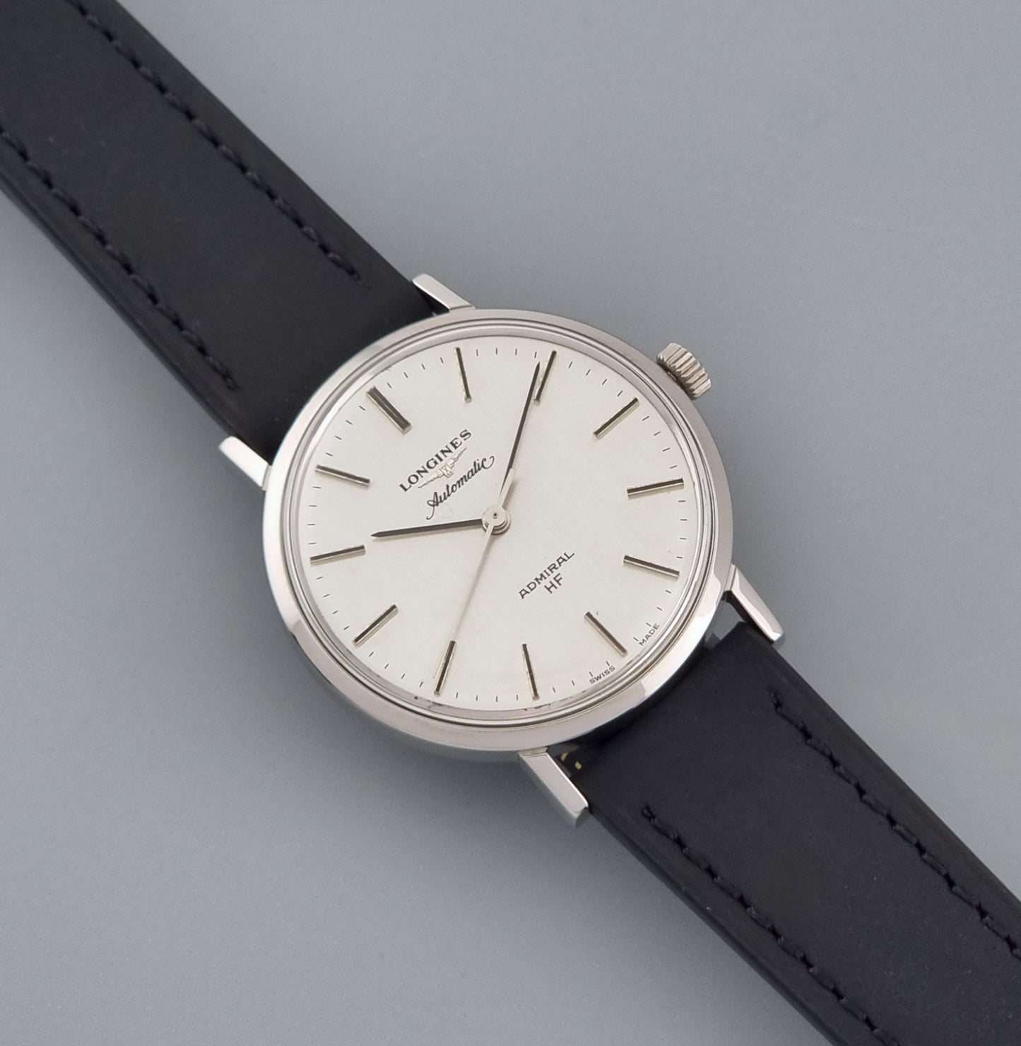 Vintage Longines Admiral Hi frequency Automatic Wristwatch 2305-1 with a black leather strap on a grey background dial