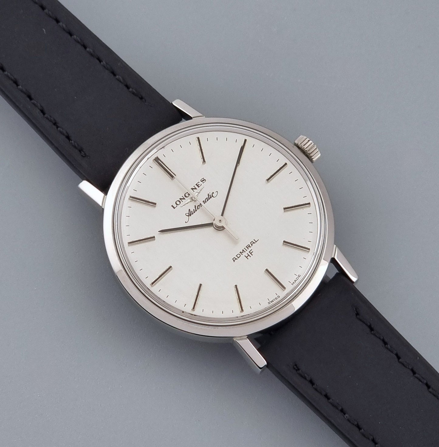 Vintage Longines Admiral Hi frequency Automatic Wristwatch 2305-1 with a black leather strap on a grey background front view