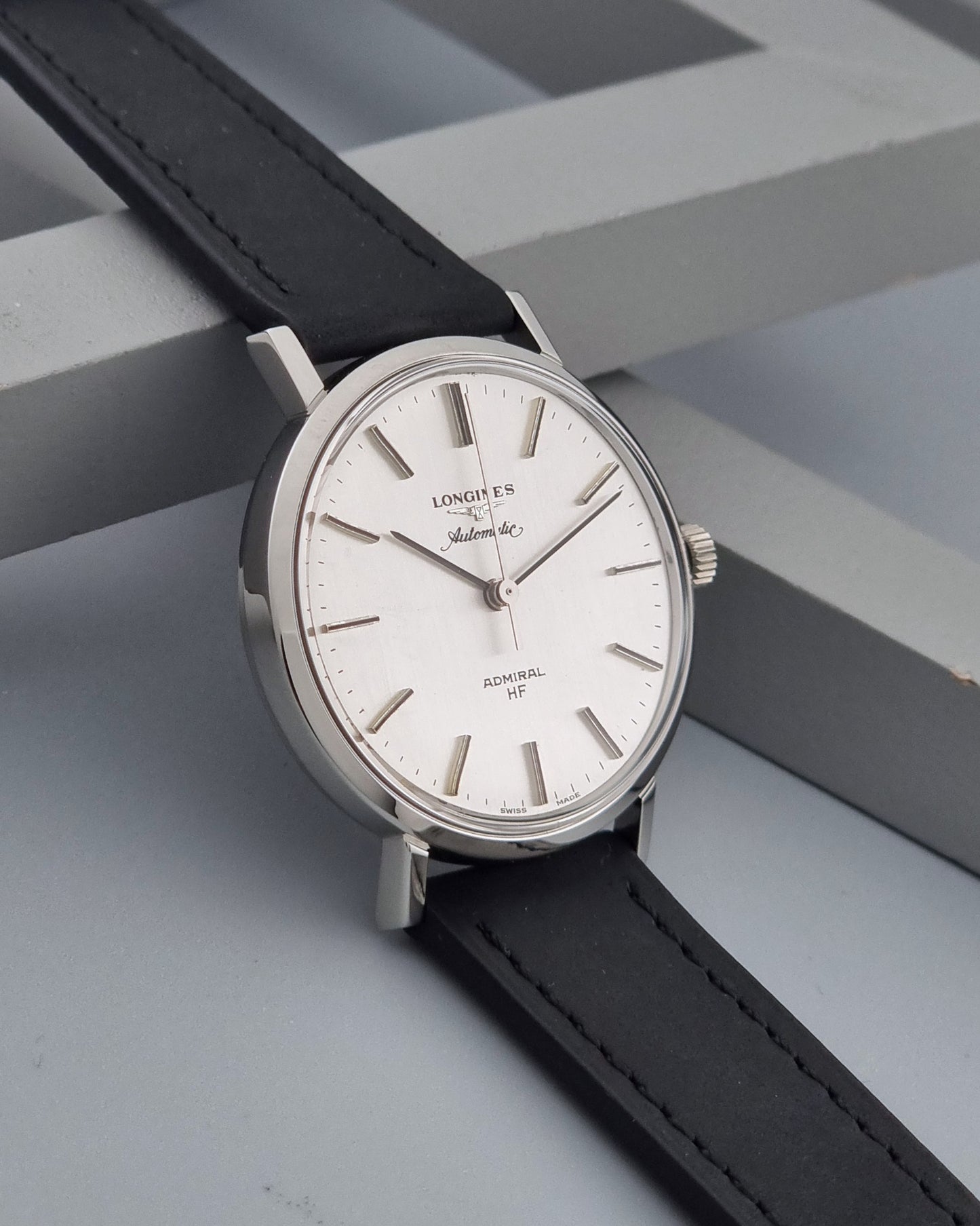 Vintage Longines Admiral Hi frequency Automatic Wristwatch 2305-1 with a black leather strap on a grey background side view