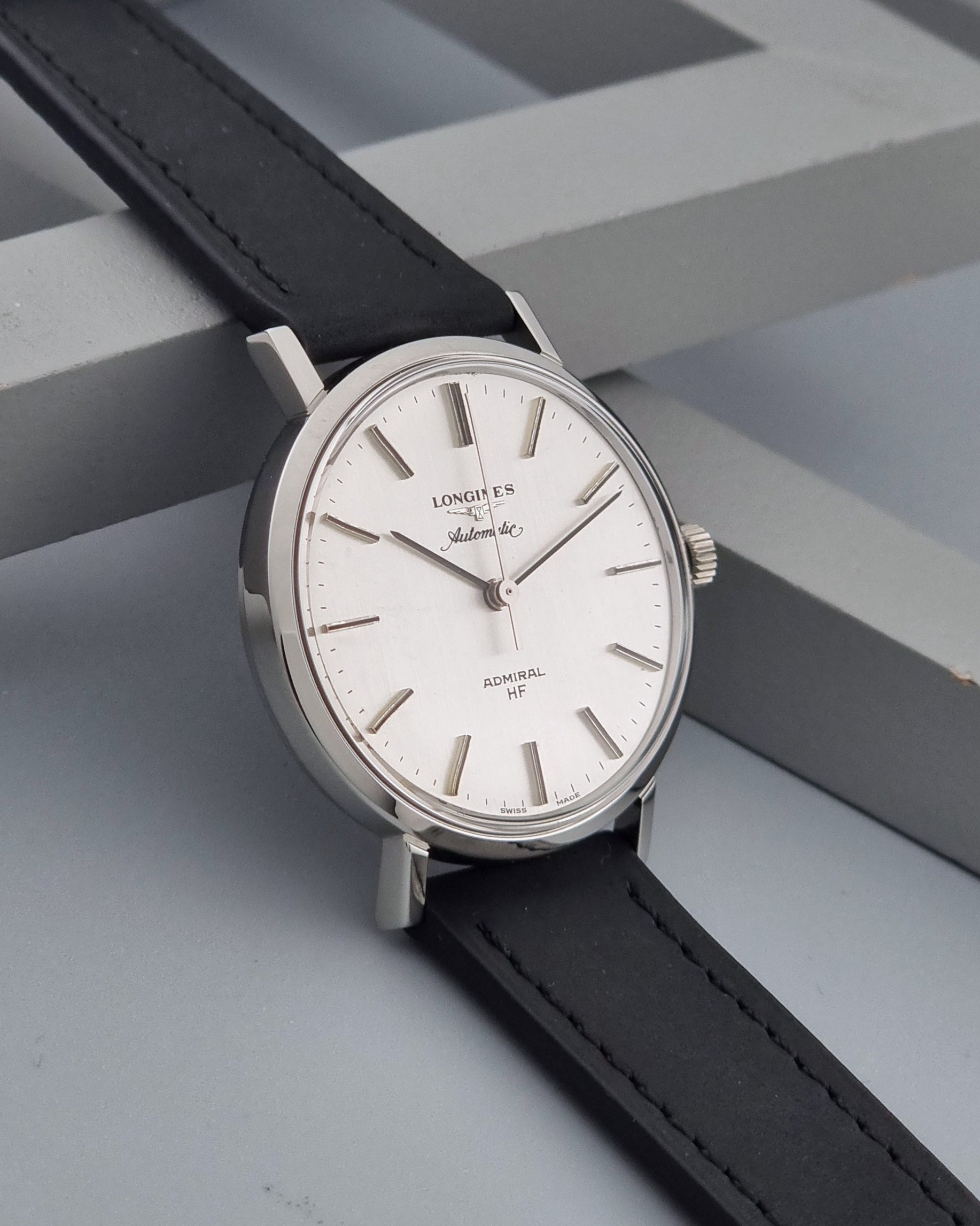 Vintage Longines Admiral Hi frequency Automatic Wristwatch 2305-1 with a black leather strap on a grey background side view