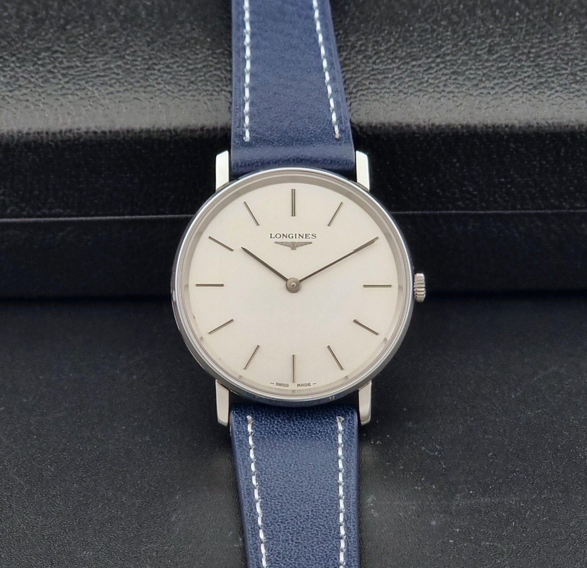 Vintage Longines Wristwatch 4127  with blue strap and silver case on a dark gray background dial view