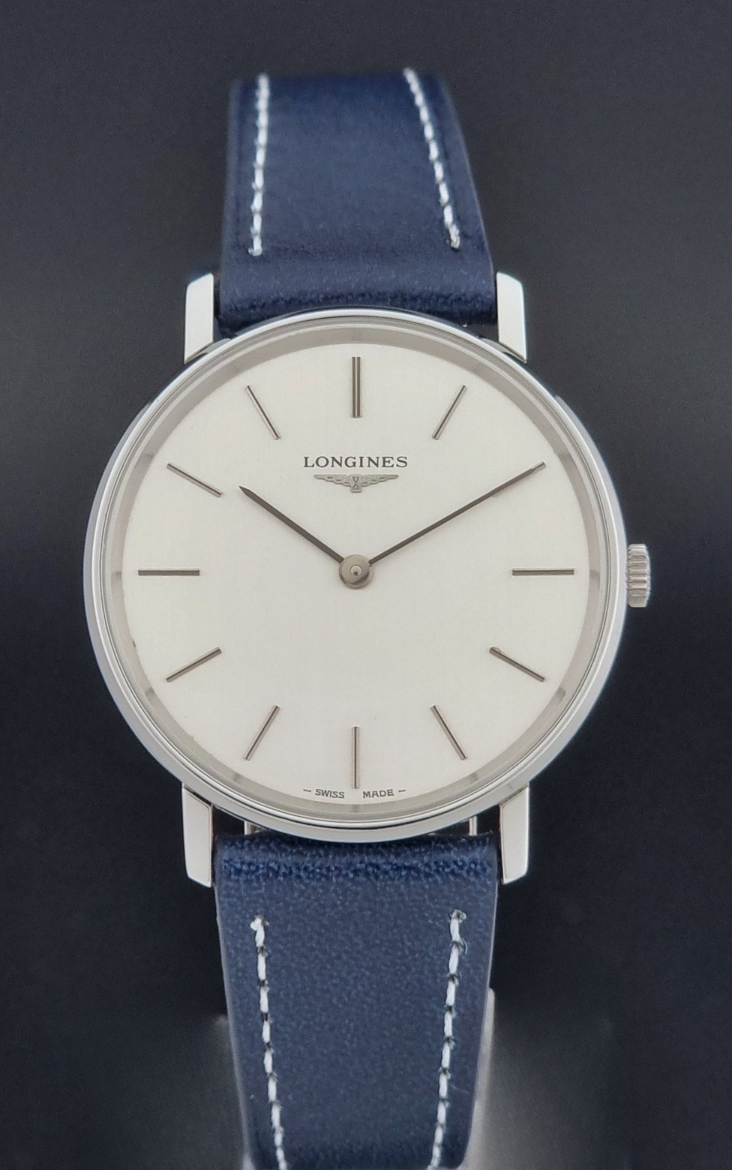 Vintage Longines Wristwatch 4127  with blue strap and silver case on a dark gray background close dial view