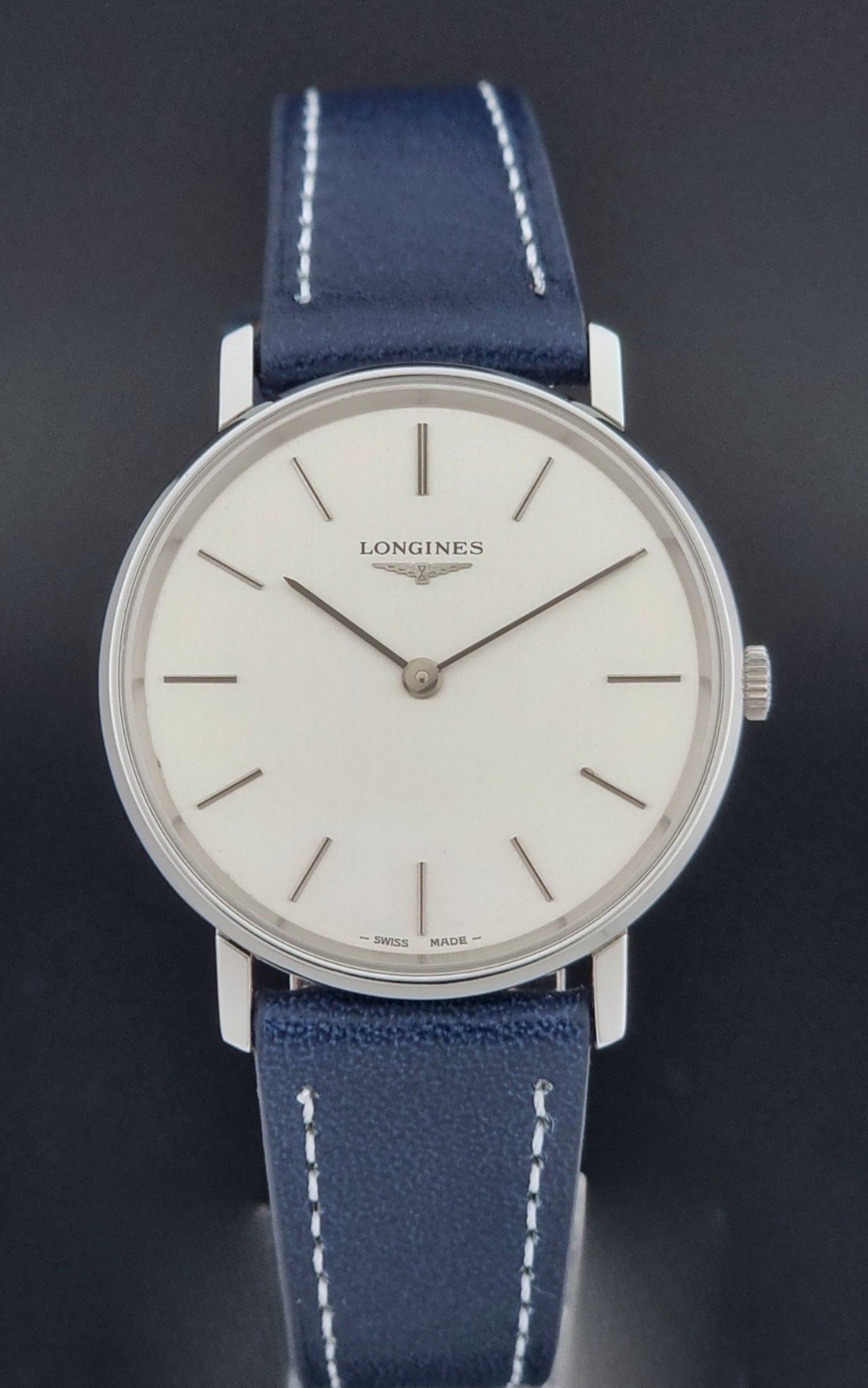 Vintage Longines Wristwatch 4127  with blue strap and silver case on a dark gray background close dial view