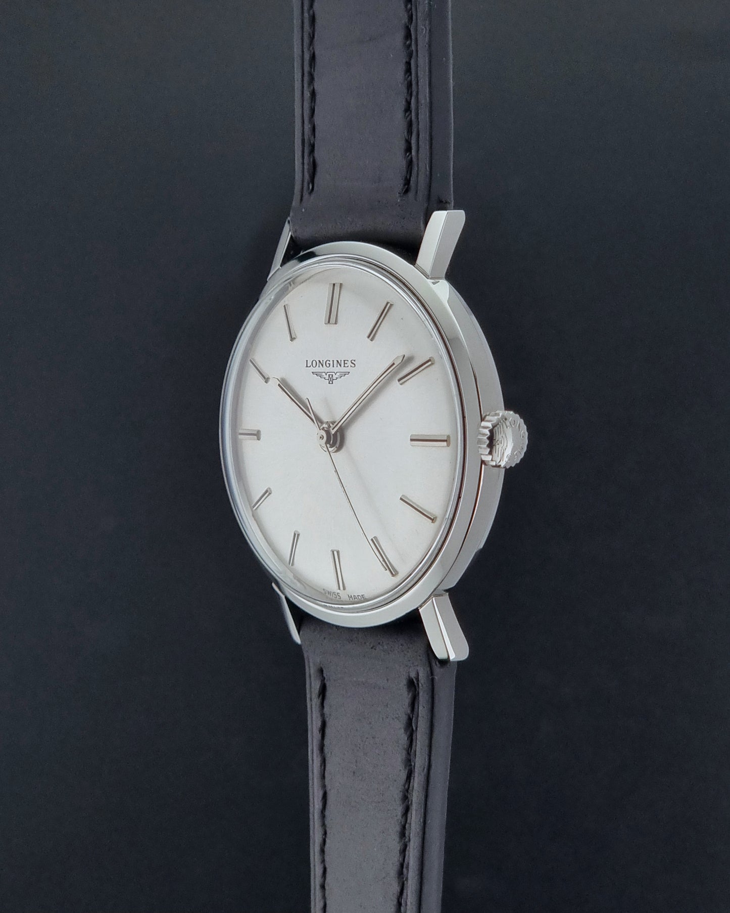 Vintage Longines 7839-5 watch with a black leather strap on a dark gray background crown profile view