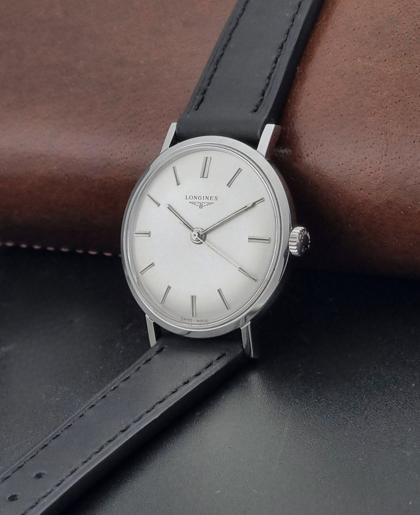 Vintage Longines 7839-5 watch with a black leather strap on a dark gray background crown view