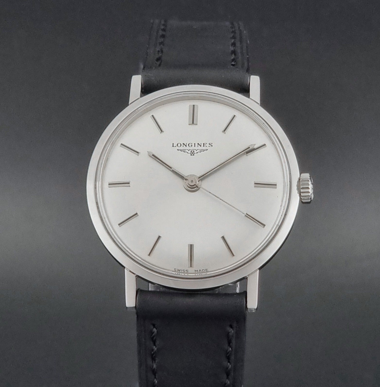 Vintage Longines 7839-5 watch with a black leather strap on a dark gray background close dial view