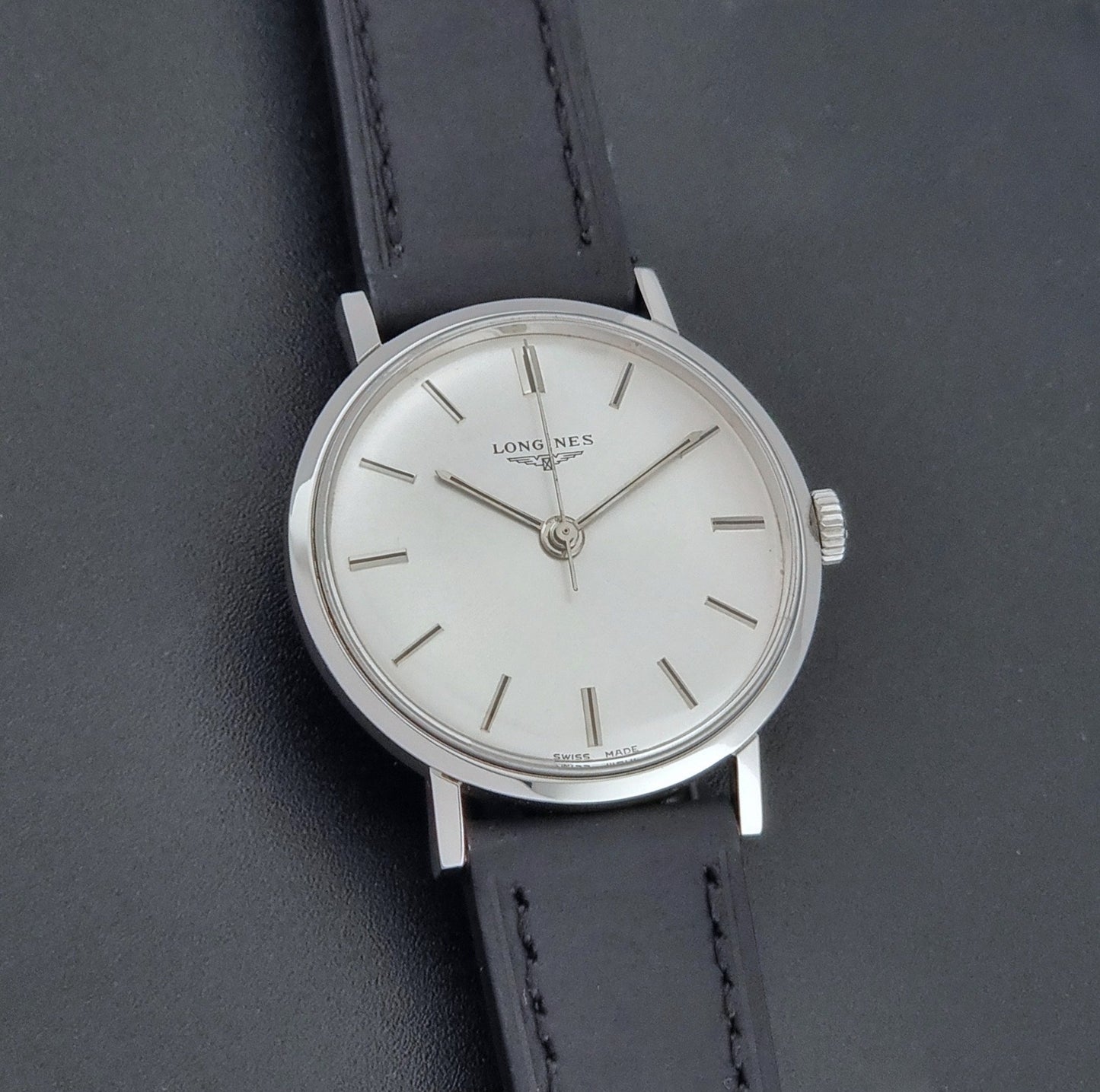 Vintage Longines 7839-5 watch with a black leather strap on a dark gray background front view