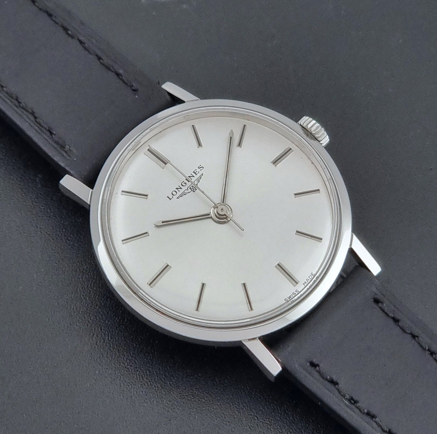Vintage Longines 7839-5 watch with a black leather strap on a dark gray background close up dial view