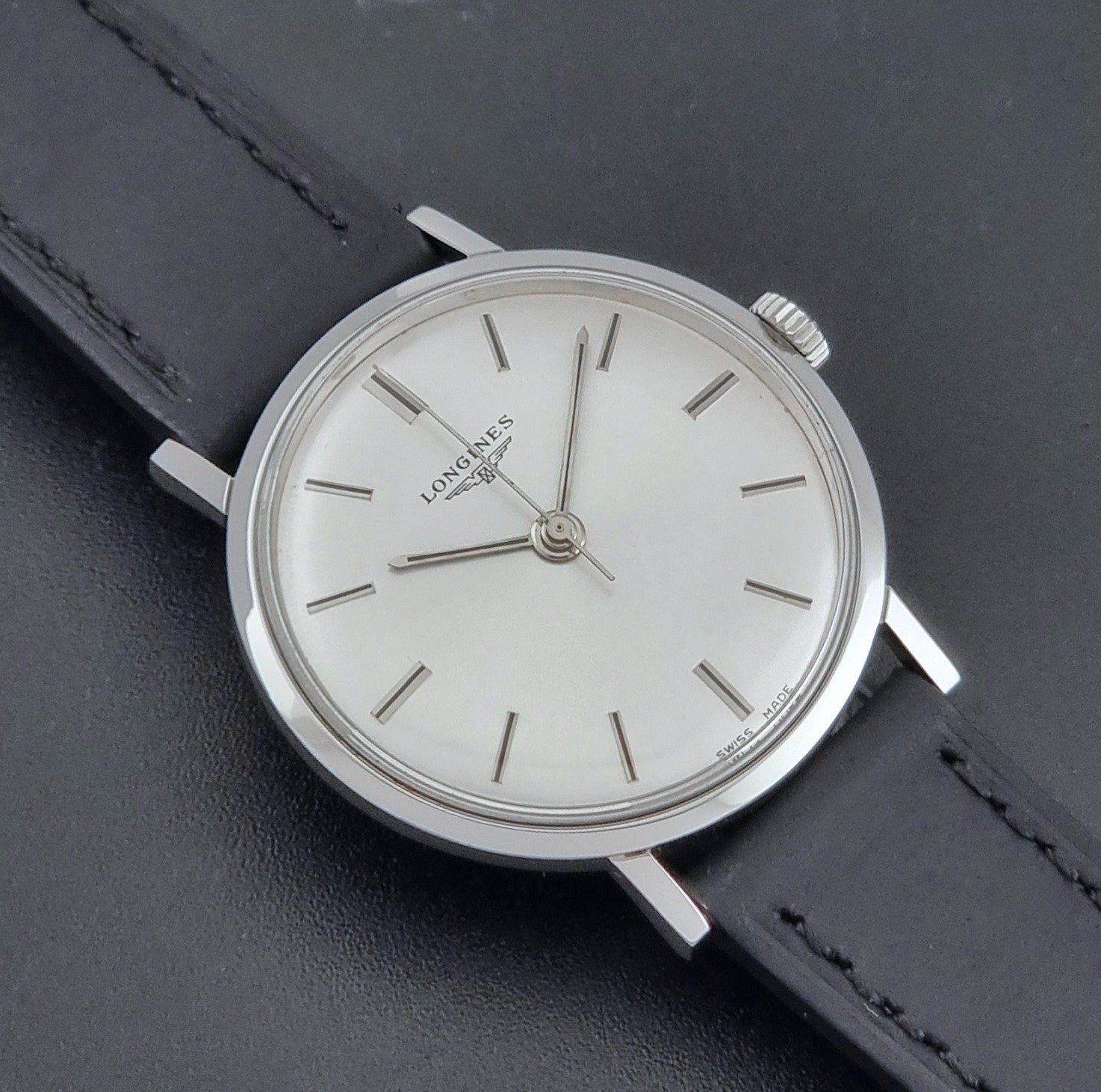 Vintage Longines 7839-5 watch with a black leather strap on a dark gray background close up dial view