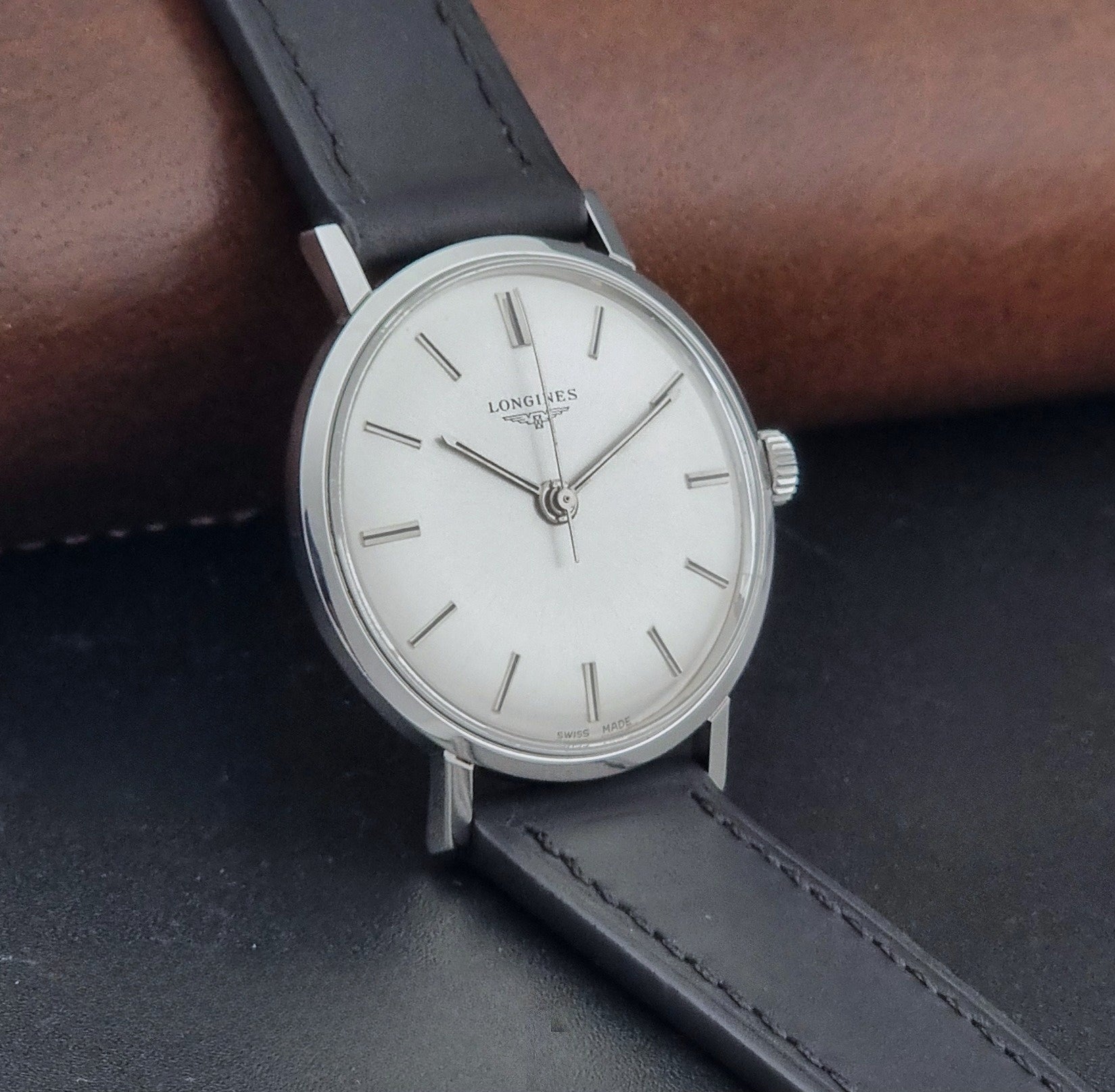 Vintage Longines 7839-5 watch with a black leather strap on a dark gray background side view