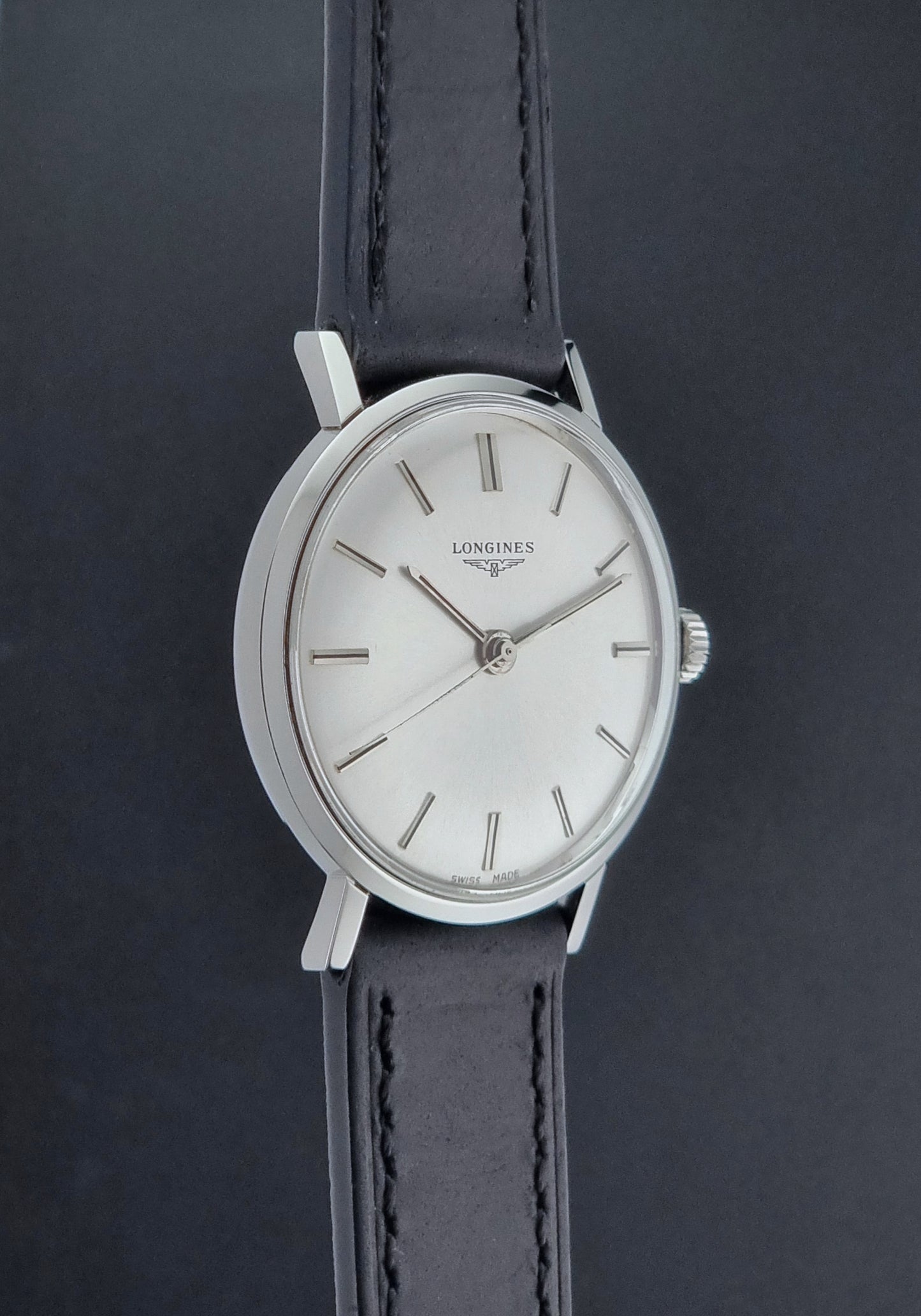 Vintage Longines 7839-5 watch with a black leather strap on a dark gray background side profile view