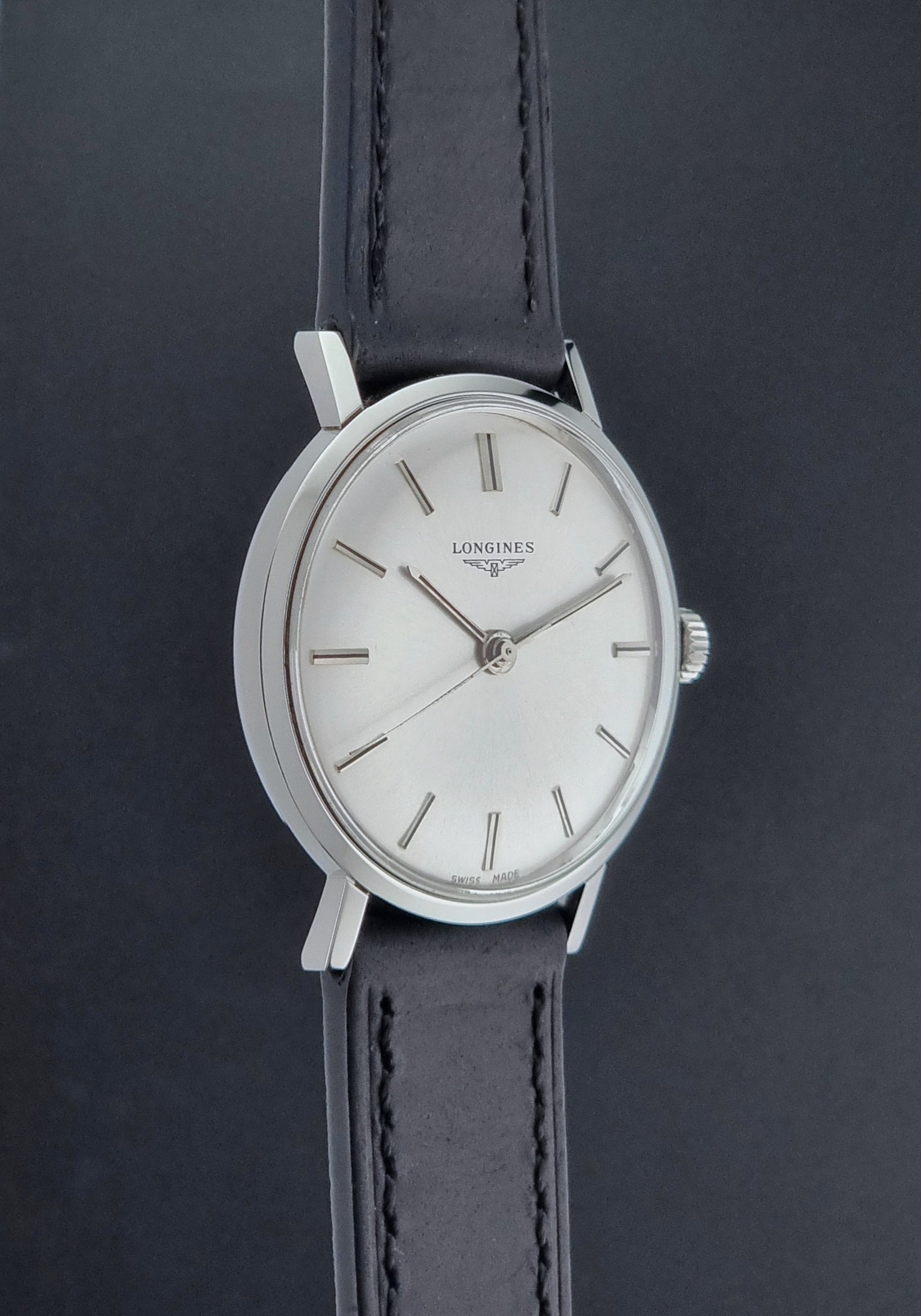 Vintage Longines 7839-5 watch with a black leather strap on a dark gray background side profile view