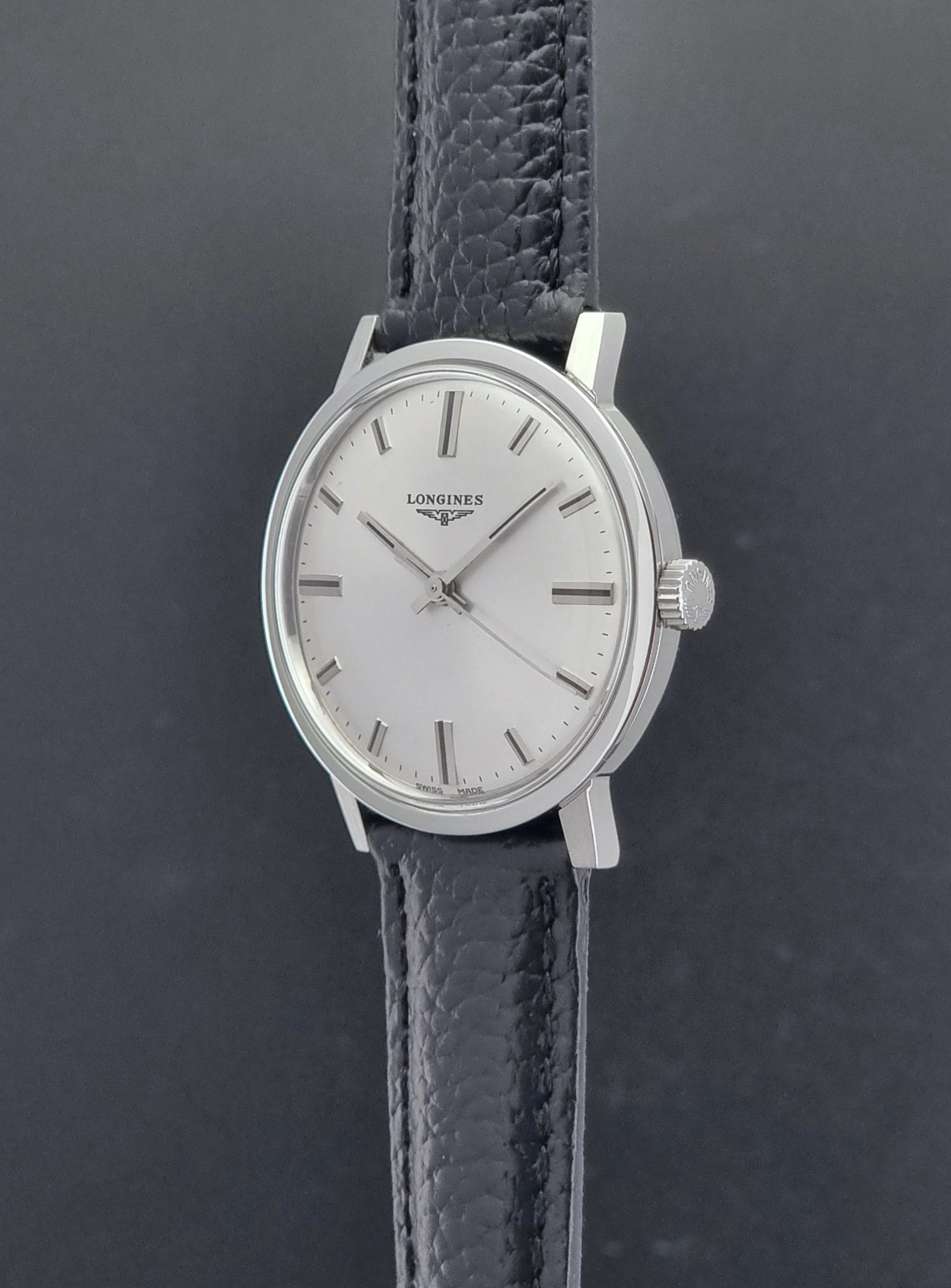 Vintage Longines 8319  Wristwatch with a black leather strap on a dark background crown profile view