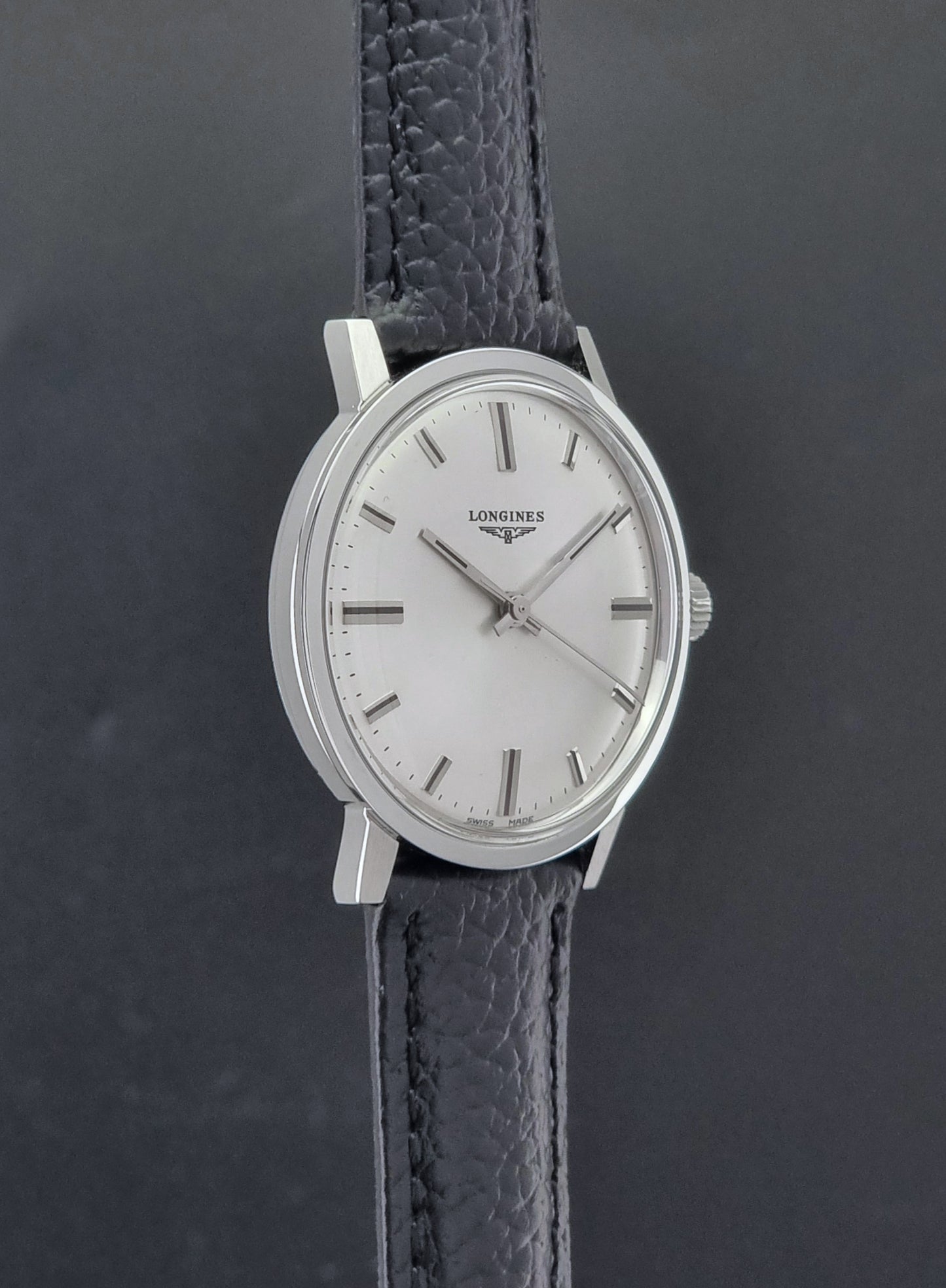 Vintage Longines 8319  Wristwatch with a black leather strap on a dark background side profile view
