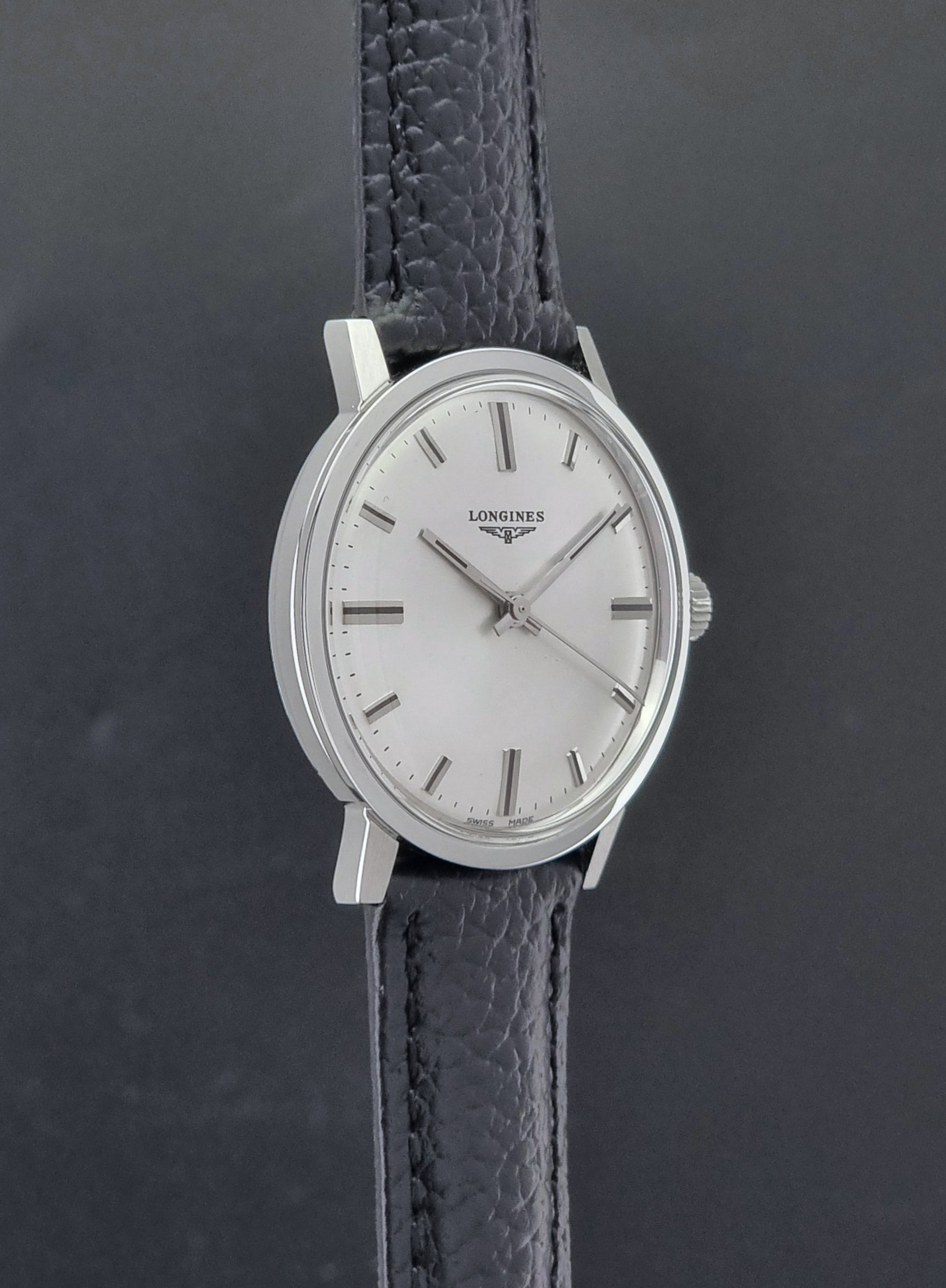 Vintage Longines 8319  Wristwatch with a black leather strap on a dark background side profile view