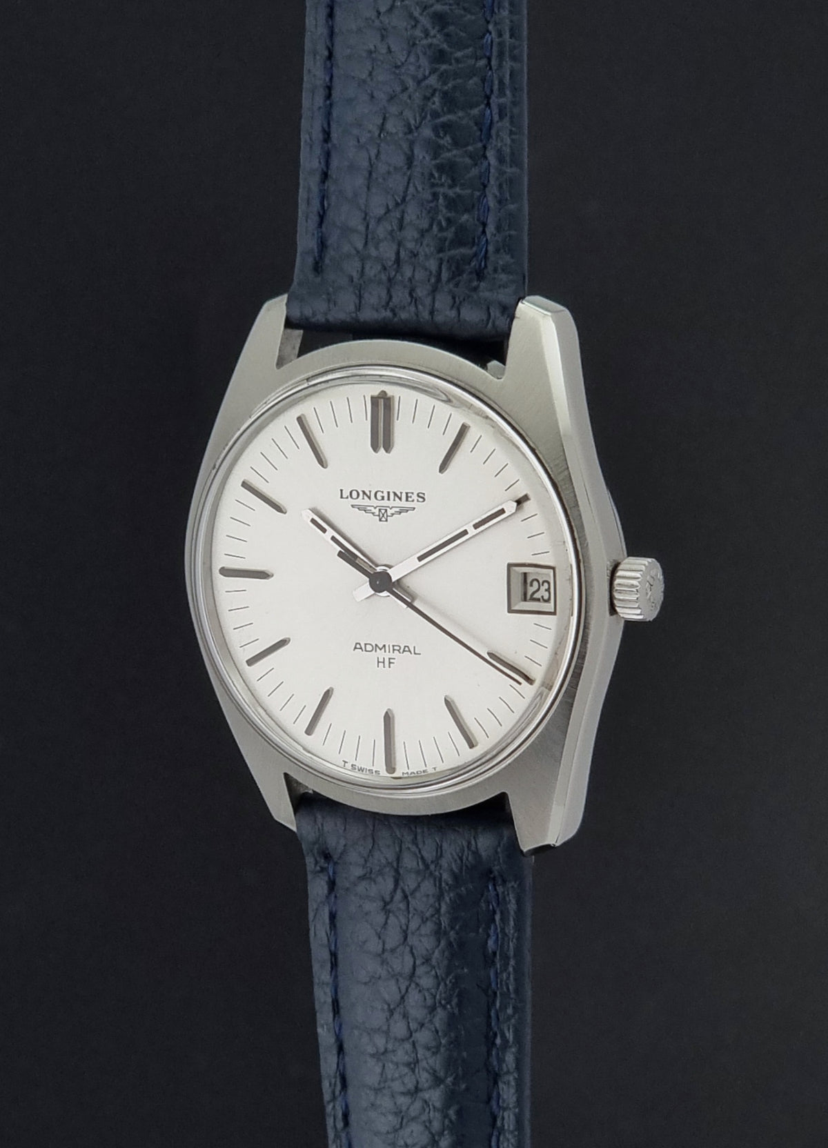 A Longines Admiral HF wristwatch with a silver-toned stainless steel case, white dial, and textured dark blue leather strap, shown against a dark background.
