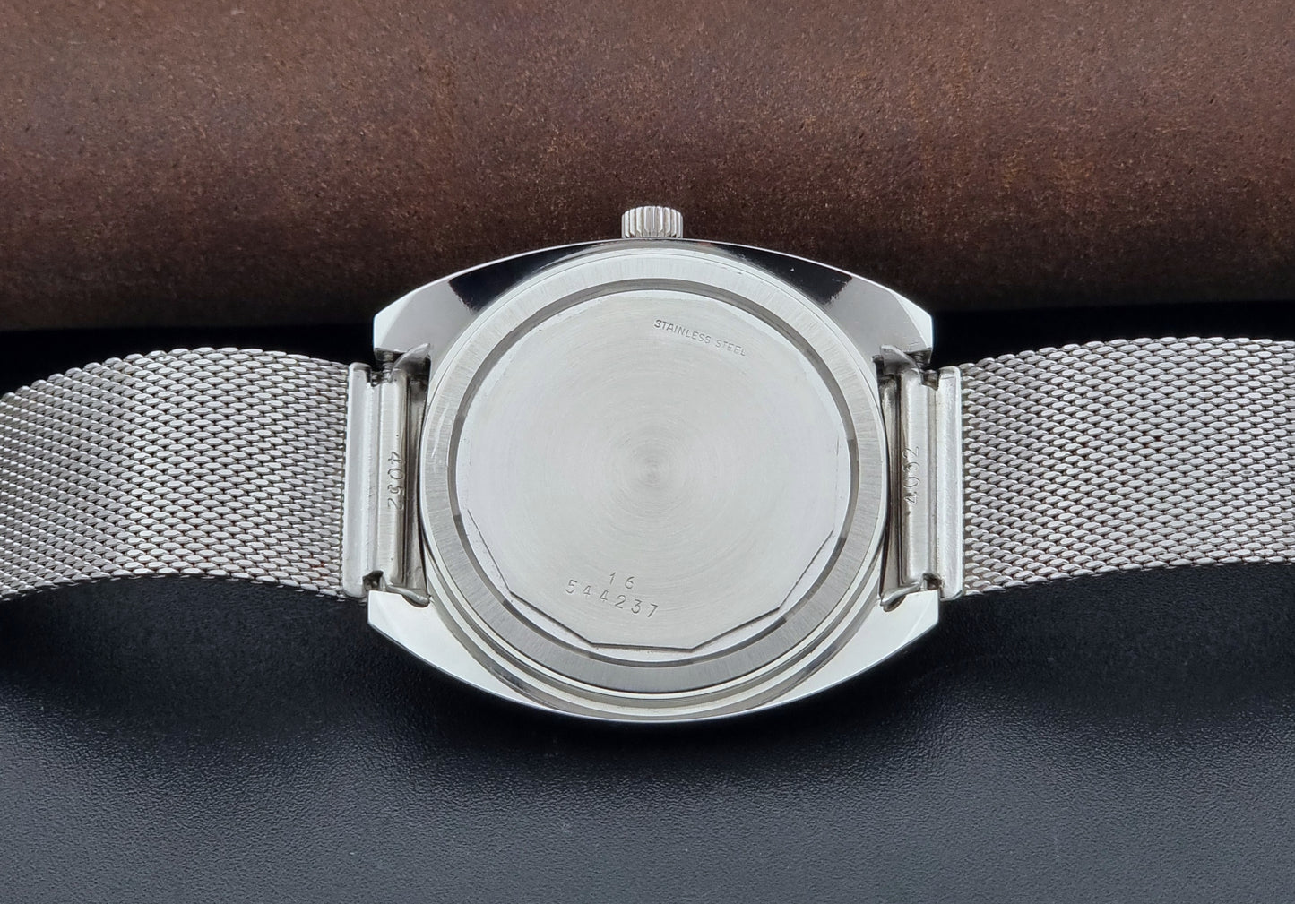 Vintage Longines Admiral Hi frequency Wristwatch 2304-2 with a mesh band on a dark gray background case back view