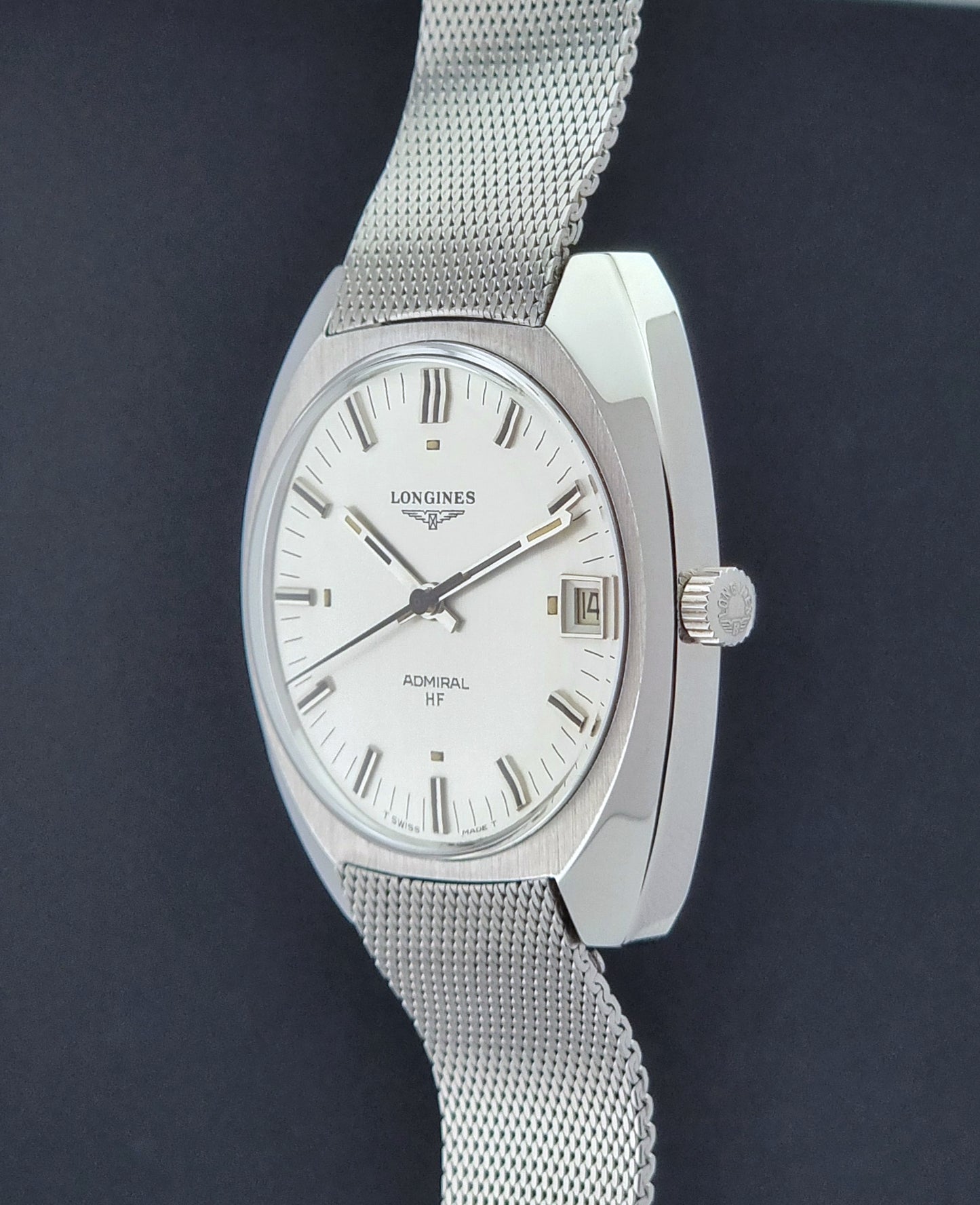 Vintage Longines Admiral Hi frequency Wristwatch 2304-2 with a mesh band on a dark gray background crown profile view