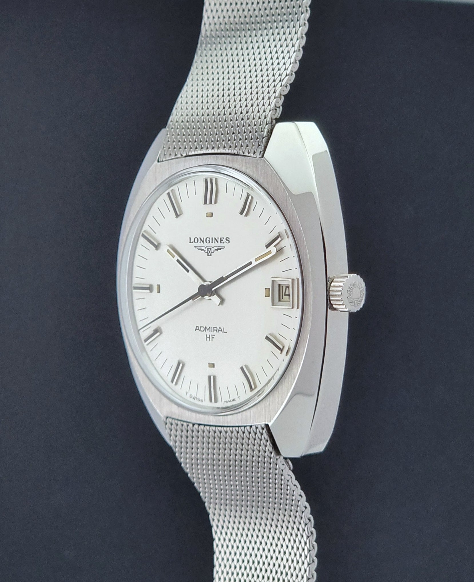 Vintage Longines Admiral Hi frequency Wristwatch 2304-2 with a mesh band on a dark gray background crown profile view