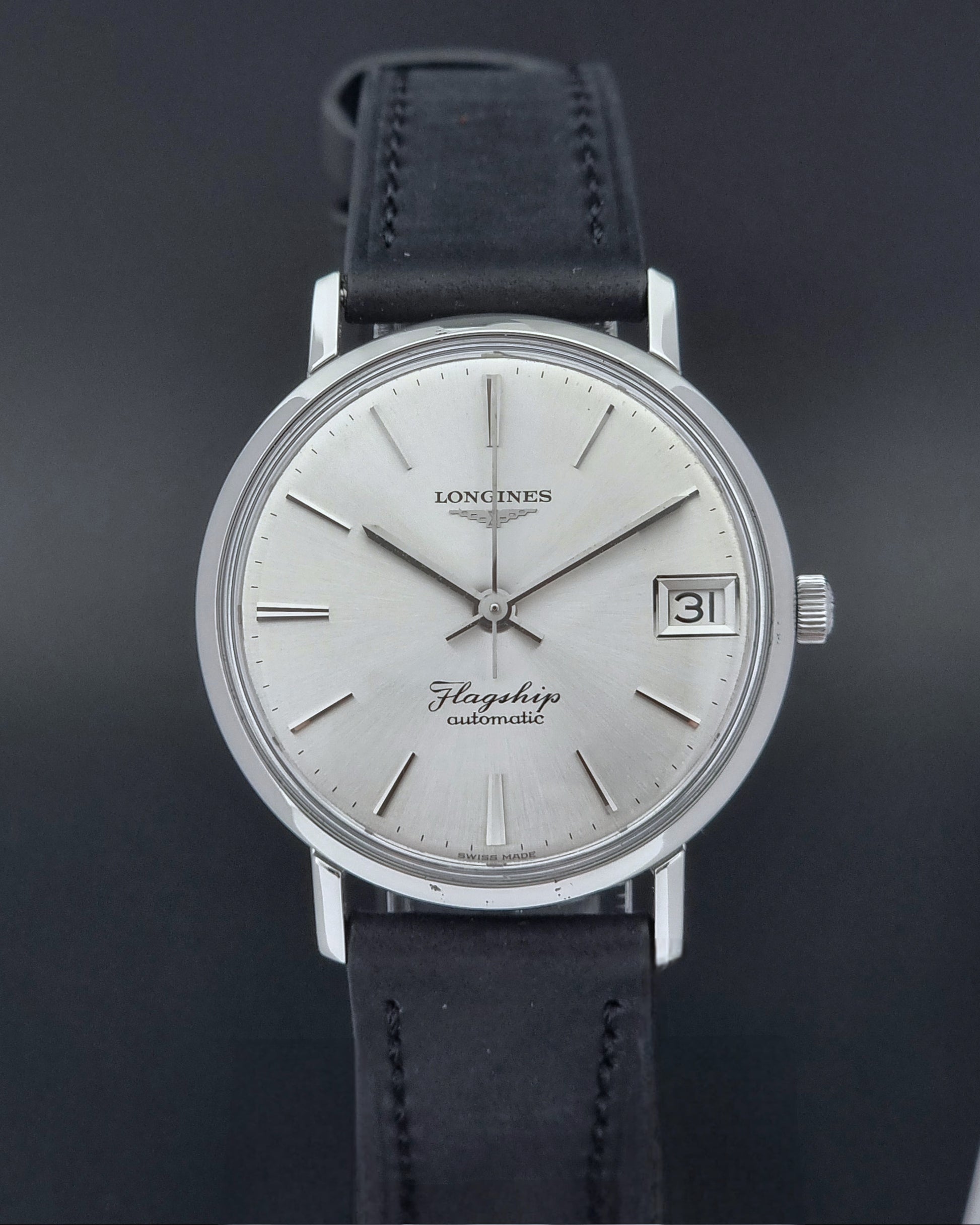 Front of a Vintage Longines Flagship watch with black leather strap on a dark background