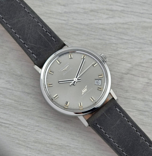 Vintage Longines Ultra-Chron Wristwatch with gray leather strap and silver case on a light gray background