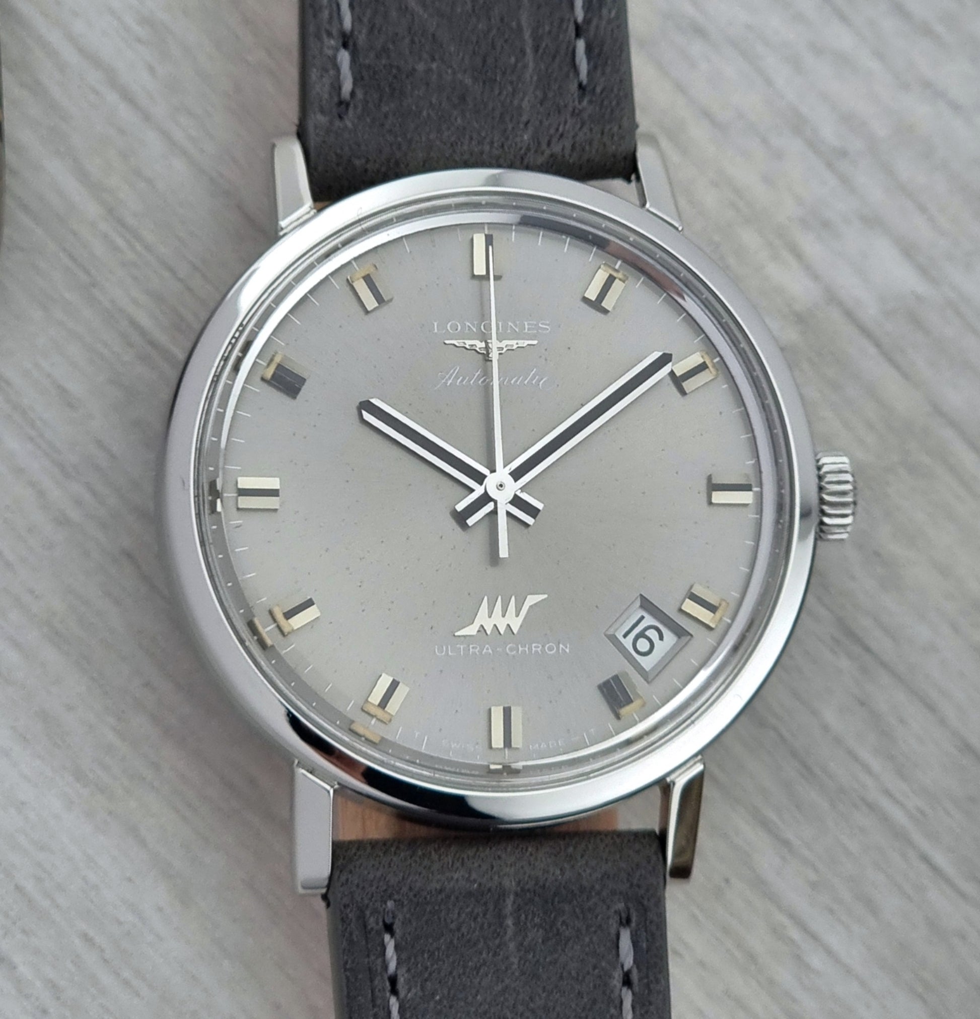 Vintage Longines Ultra-Chron Watch with gray strap and silver case on a light gray background