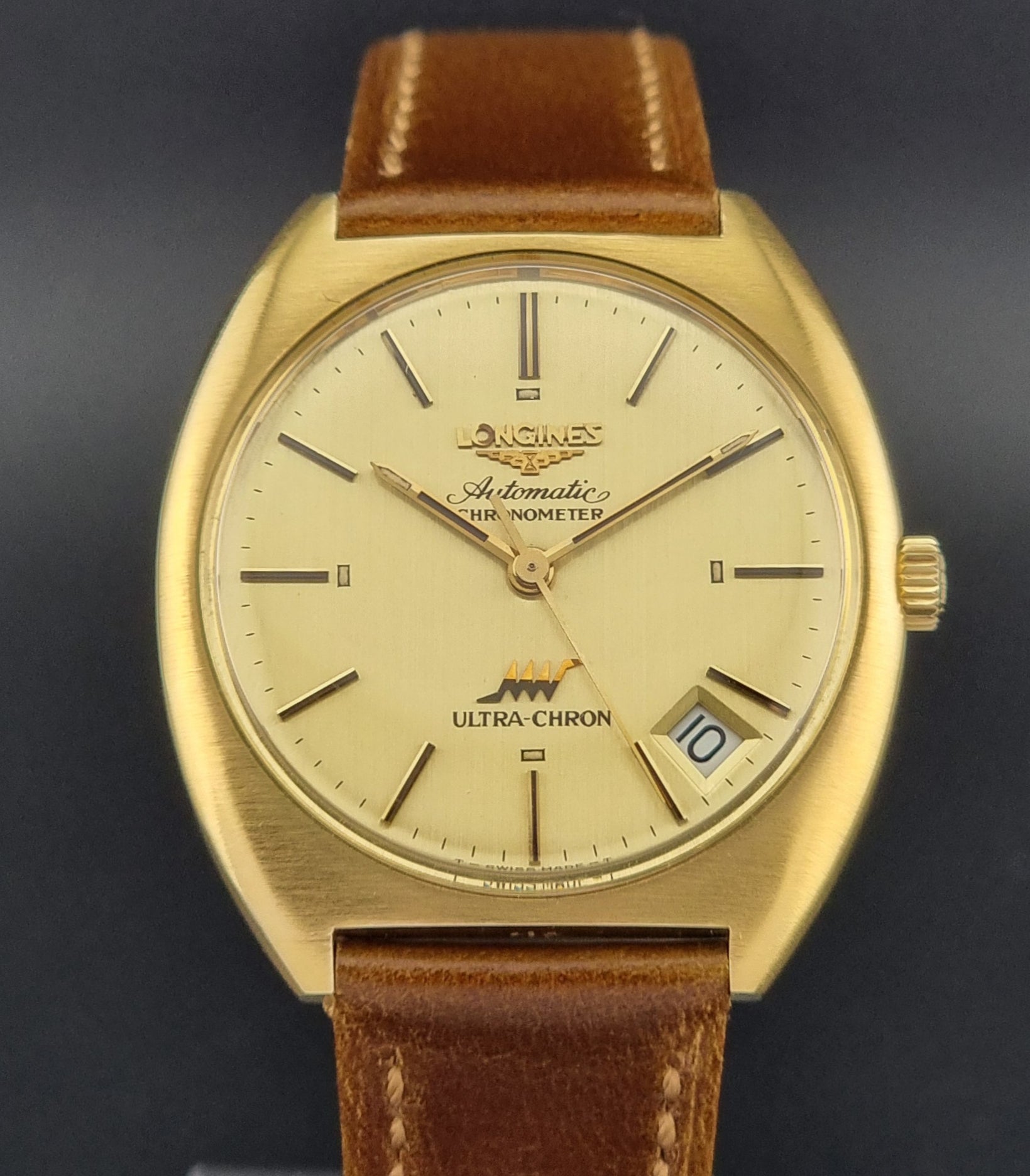 Vintage Longines Gold wristwatch with brown leather strap on a dark background