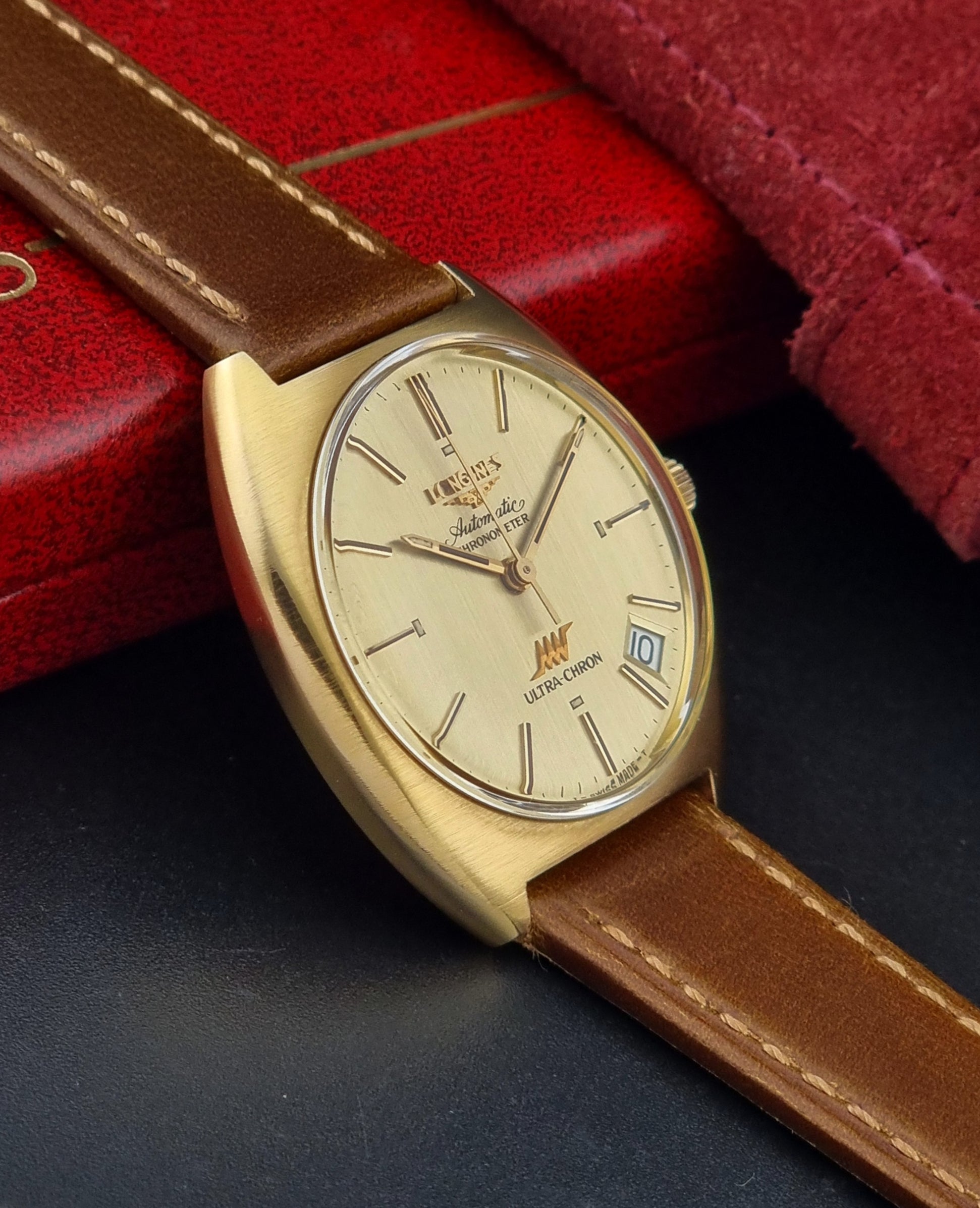 Vintage Longines Gold wristwatch with brown leather strap on a dark surface