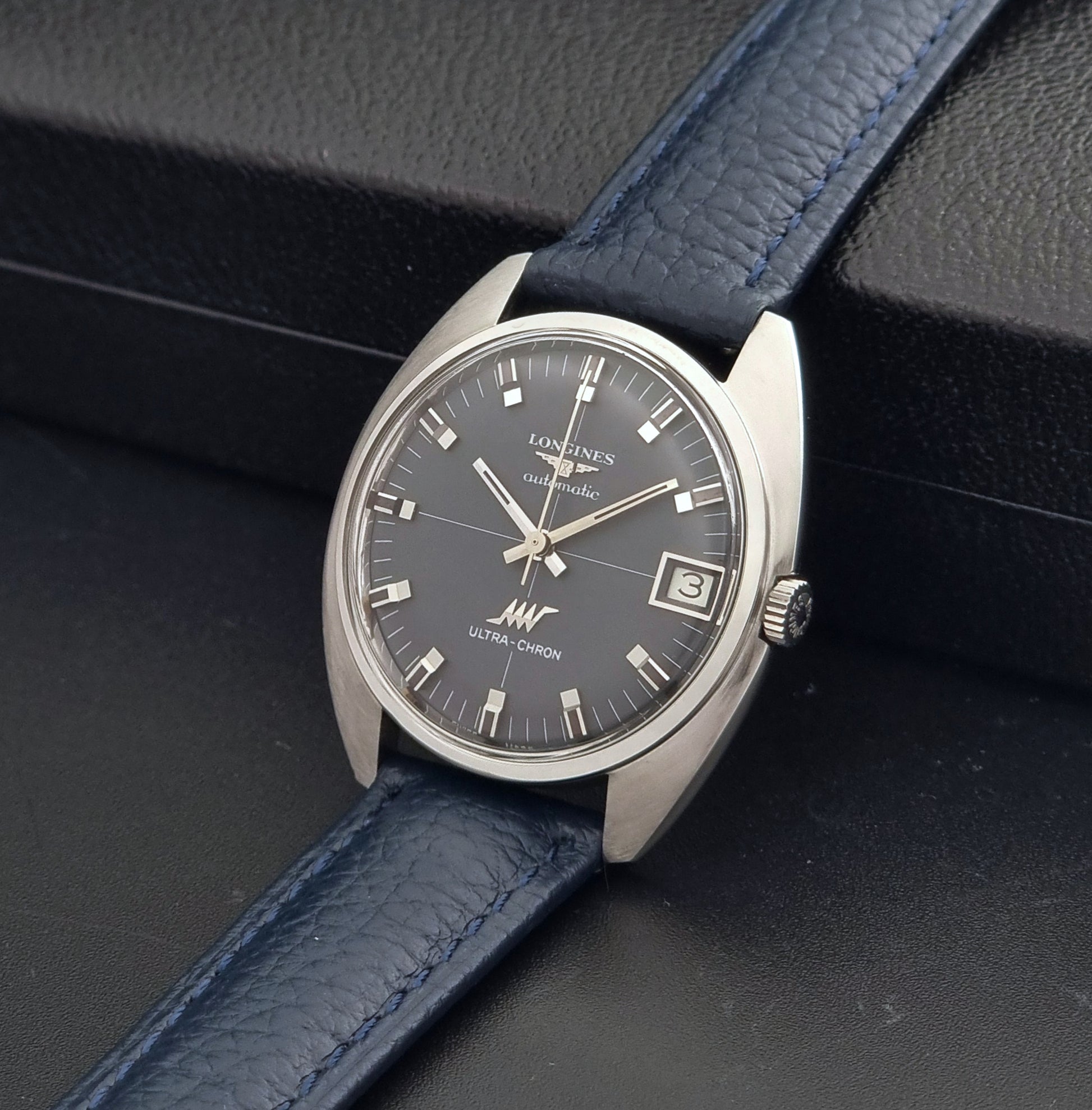 Vintage Longines watch ULTRA-CHRON 8071-2 with blue leather strap and silver case on a dark gray background crown view