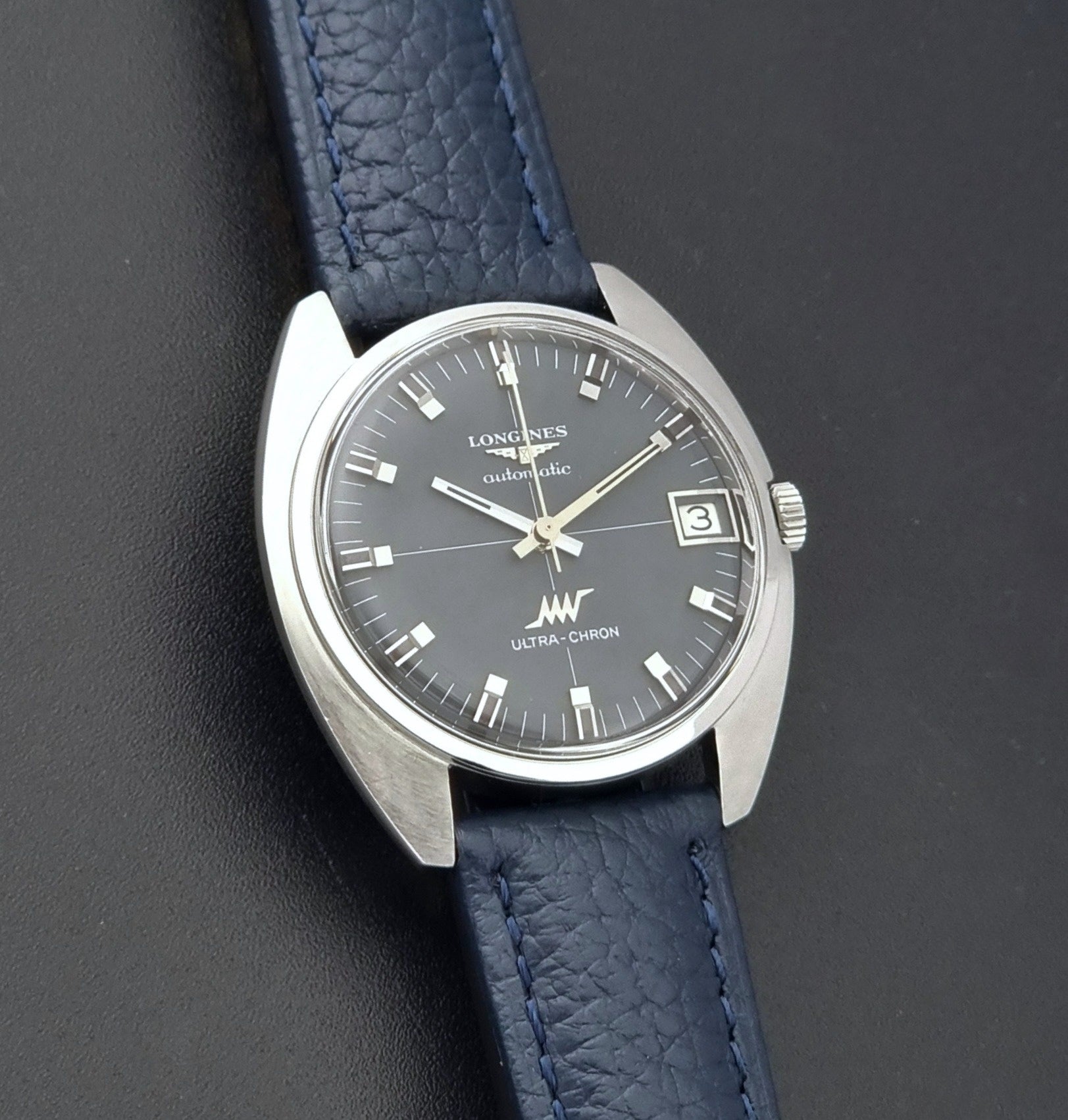 Vintage Longines watch ULTRA-CHRON 8071-2 with blue leather strap and silver case on a dark gray background front view