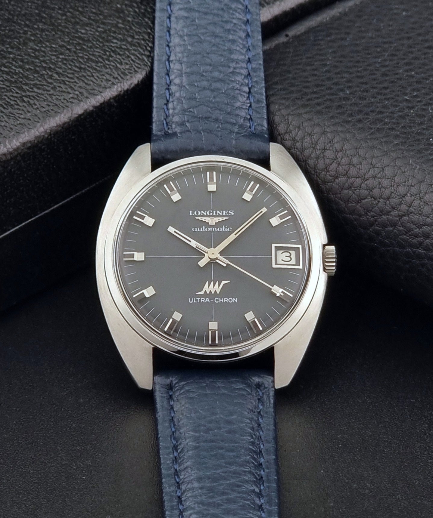 Vintage Longines watch ULTRA-CHRON 8071-2 with blue leather strap and silver case on a dark gray background dial view