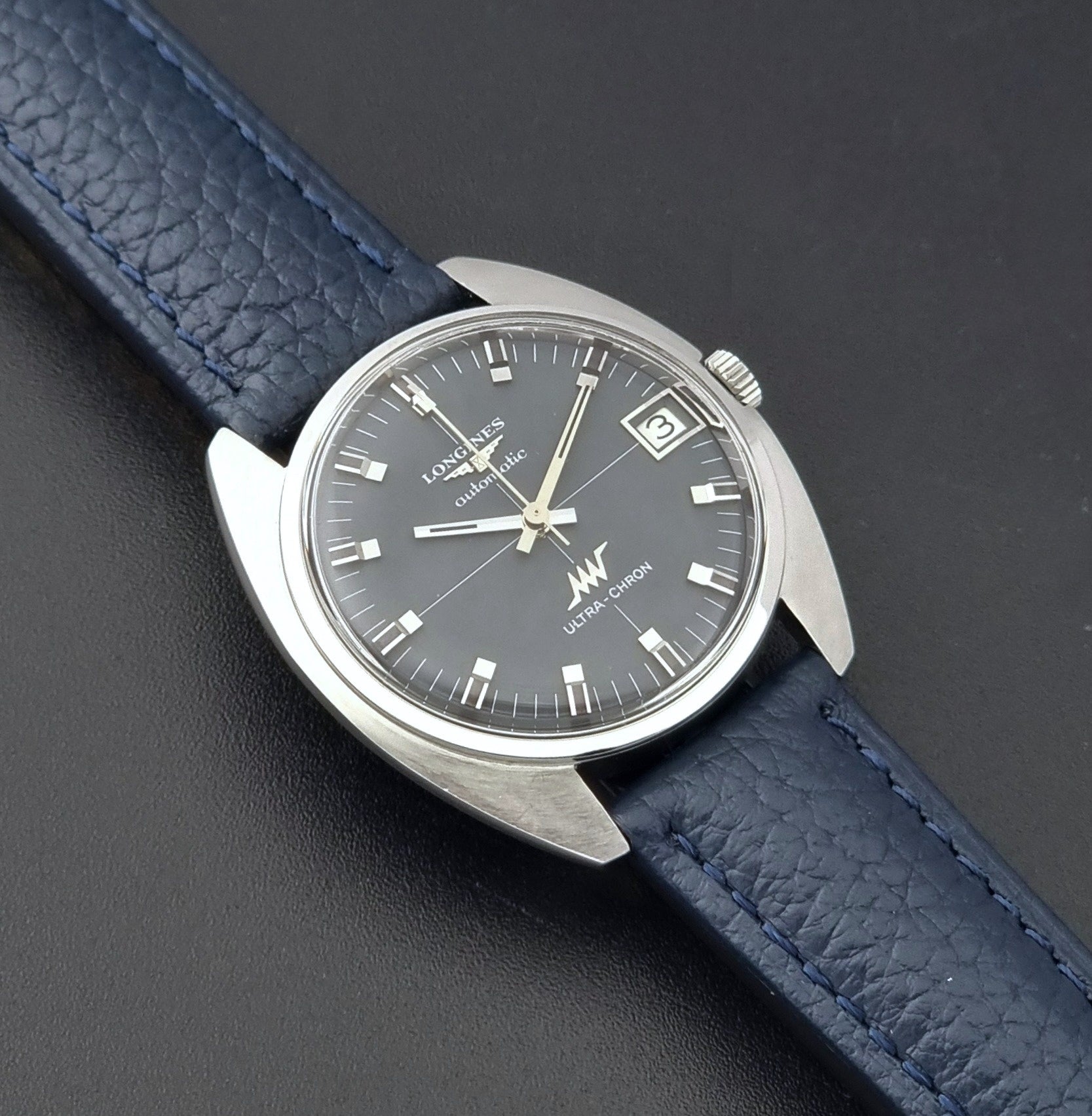 Vintage Longines watch ULTRA-CHRON 8071-2 with blue leather strap and silver case on a dark gray background close up dial view