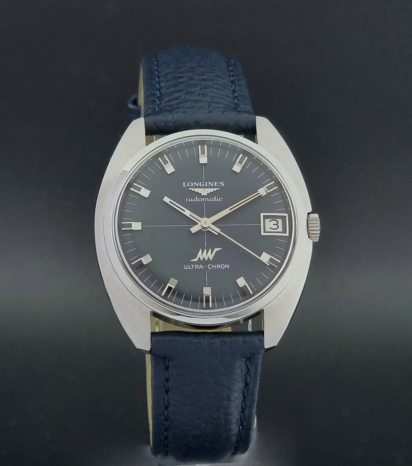 Vintage Longines watch ULTRA-CHRON 8071-2 with blue leather strap and silver case on a dark gray background close dial view