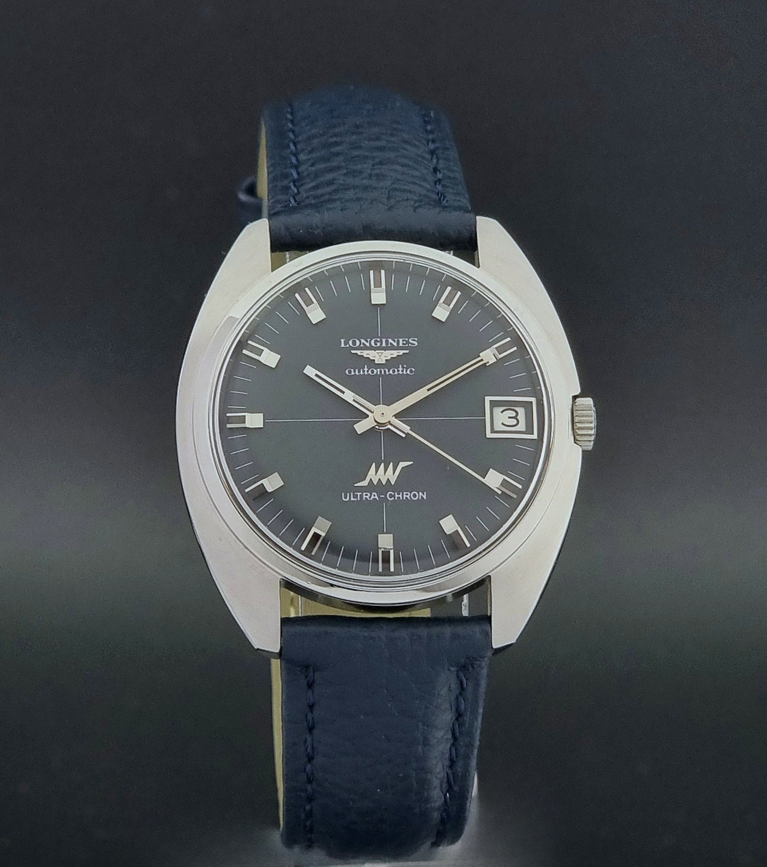 Vintage Longines watch ULTRA-CHRON 8071-2 with blue leather strap and silver case on a dark gray background close dial view