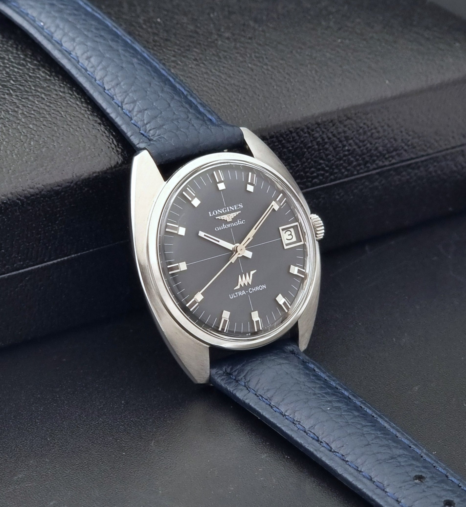 Vintage Longines watch ULTRA-CHRON 8071-2 with blue leather strap and silver case on a dark gray background side view
