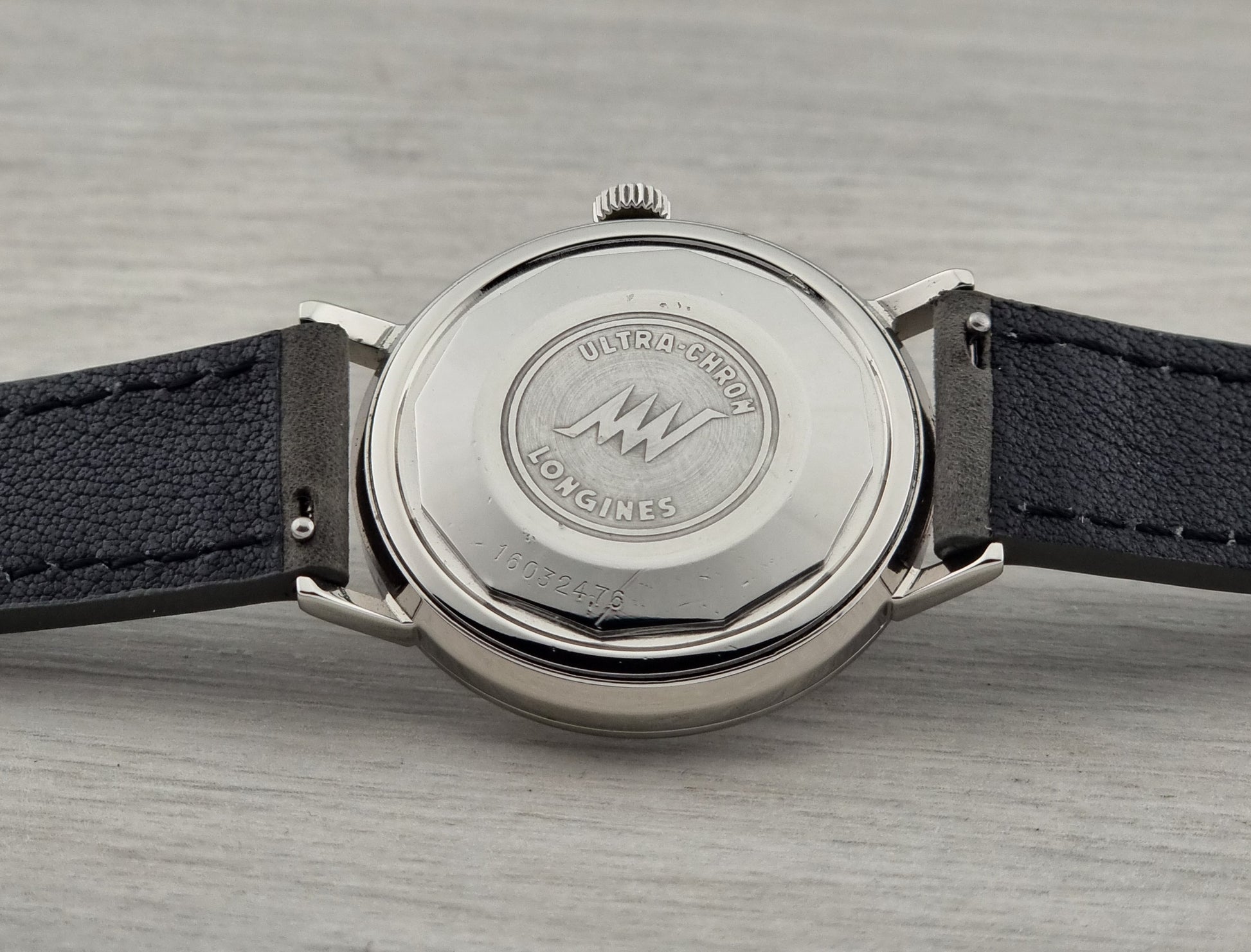 Close-up of a watch with a visible brand logo on a gray surface