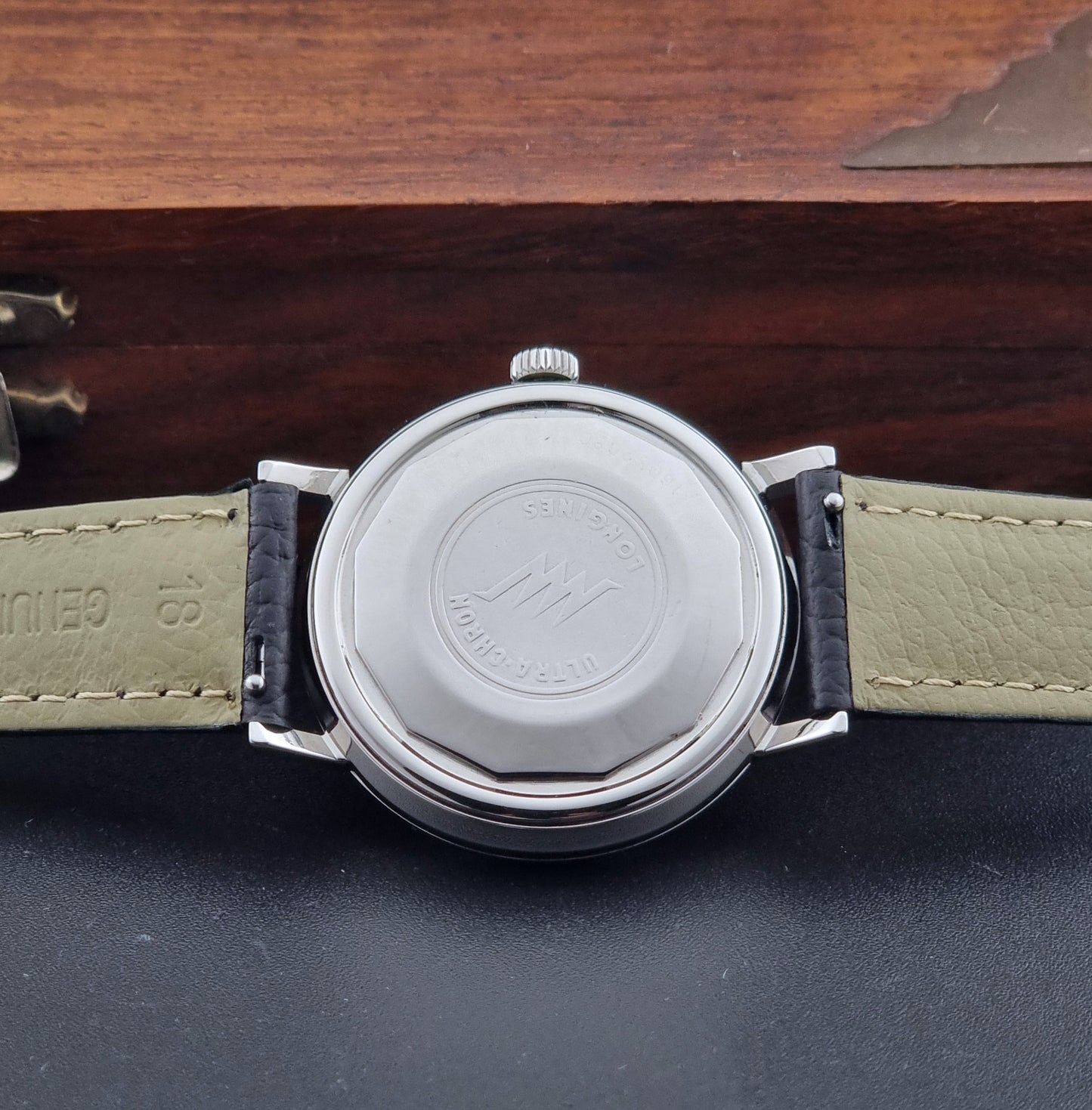 Vintage Longines ULTRA-CHRON 8383-1 with black leather strap and silver case on a dark gray background case back view
