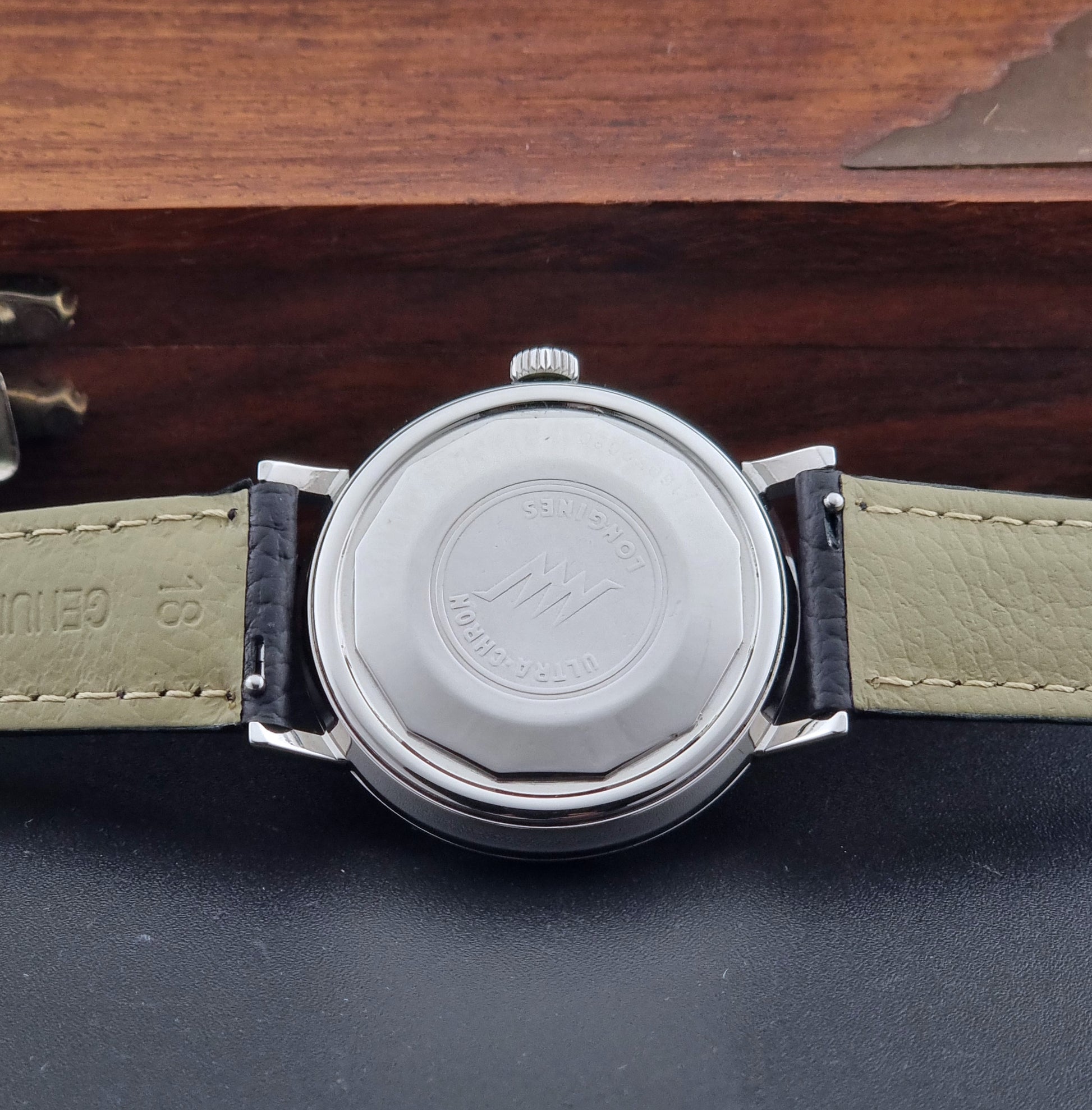 Vintage Longines ULTRA-CHRON 8383-1 with black leather strap and silver case on a dark gray background case back view