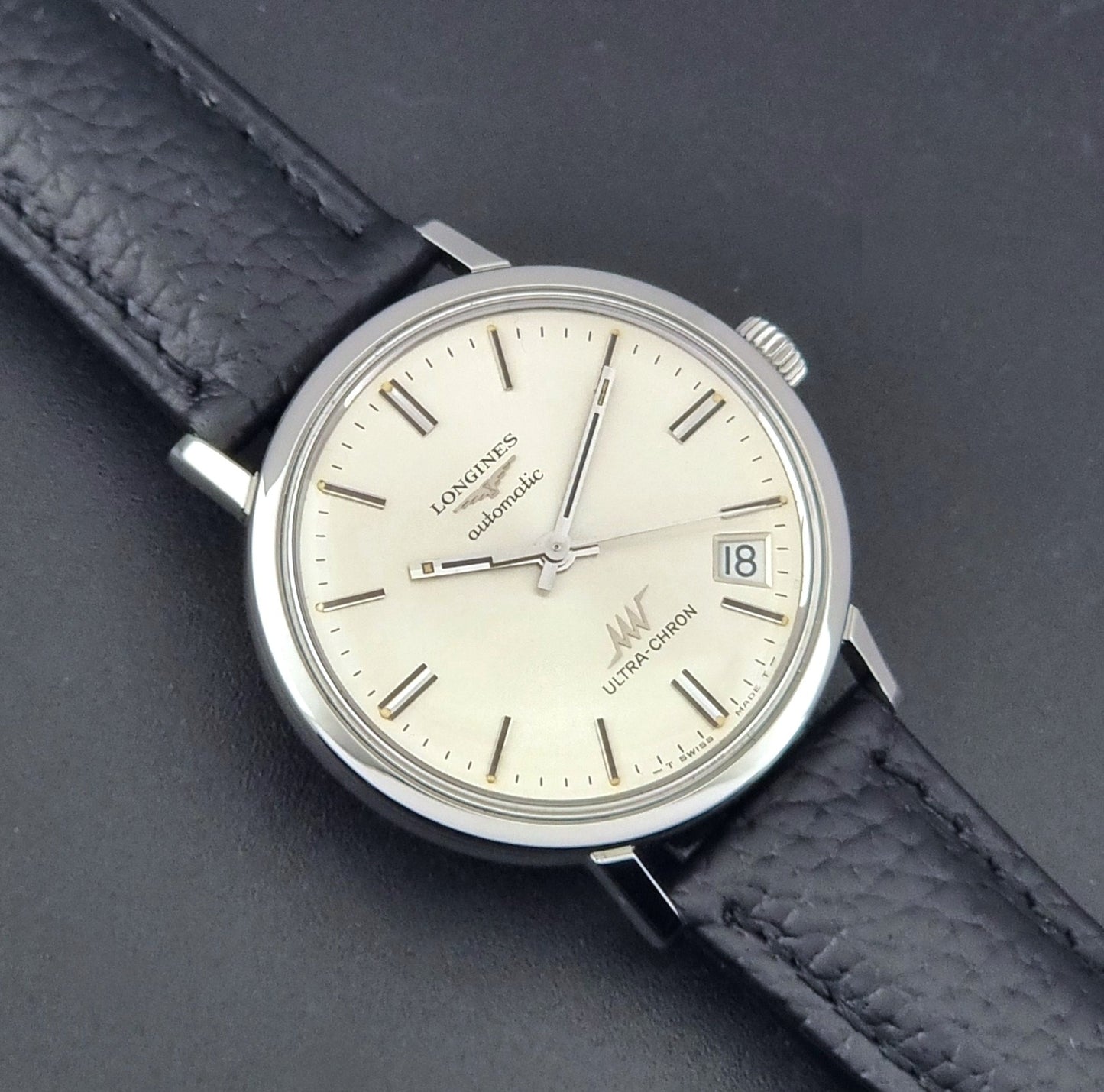 Vintage Longines ULTRA-CHRON 8383-1 with black leather strap and silver case on a dark gray background close up dial view